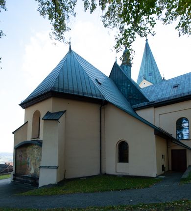 Zdjęcie nr 25: Kościół orientowany, jednonawowy, z krótkim zakończonym wielobocznie prezbiterium, przy którym od północy zakrystia z nowszym przedsionkiem; przy nawie od północy prostokątna kaplica Różańcowa (1712 r.), od zachodu wieża na rzucie kwadratu, od południa drewniana kruchta. Wewnątrz stropy. Arkada tęczy szeroka półkolista. Zewnątrz mury opięte przyporami, tynkowane. Dachy dwuspadowe i pulpitowe. Na kalenicy dachu nawy wieżyczka na sygnaturkę z datą 1878. Okna prostokątne zamknięte półkoliście. Dwa portale kamienne prostokątne. Wieża dołem gotycka, nadbudowana w stylu pseudoromańskim; trójkondygnacyjna, dołem z narożnikami artykułowanymi boniowaniem, narożniki górnej kondygnacji ujęte lizenami połączonymi fryzem arkadkowym. Elewacje wieży zwieńczone trójkątnymi szczytami i ostrosłupowym hełmem krytym blachą.