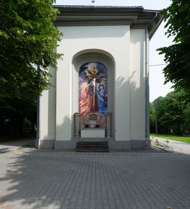 Zdjęcie nr 12: Kościół murowany, składa się z nawy i zwróconego na południe prezbiterium, do którego przylega zakrystia, nad którą znajduje się skarbiec; od północy wieża. Prezbiterium jest węższe od nawy, o zaokrąglonych narożach, oddzielone od prostokątnej nawy łukiem tęczowym. Ściany kościoła gładkie, przeprute półkolistymi oknami – dwoma w prezbiterium, sześcioma w nawie. Od zachodu chór wsparty na dwóch kolumnach, z balustradą wyłamaną na środku, dekorowaną u spodu lambrekinem. Ściany kościoła gładkie, w dolnej partii osłonięte drewnianą boazerią, z wnęką na chrzcielnicę po lewej i drugą na drzwi z prawej strony. Wnętrze przekrywają stropy – zwierciadlany w prezbiterium i płaski  z fasetami w nawie. Na nich oraz w górnej partii ścian polichromia. Nad prezbiterium wizerunek zmartwychwstałego Chrystusa, nad nawą zakomponowana w kole scena adoracji Najświętszej Marii Panny przez apostołów, poniżej, na ścianach medaliony z postaciami ważnych osobistości, świętych i aniołów. Główne drzwi od północy, boczne od zachodu. 
Kościół posadowiony na cokole. Elewacja frontowa ze zdwojonym ryzalitem, którego środek odpowiada szerokości wieży; podziały poziome przeprowadzone przy pomocy gzymsów. Na osi wejście i  okno, oba w boniowanym obramieniu. Okno ujmuje polichromowana scena Zwiastowania. Ryzalit wieńczy trójkątny fronton. Cofnięty ryzalit w dolnej partii boniowany, wyżej gładki, zwieńczony ćwierćkolistymi fragmentami przerwanego przyczółka. Boki elewacji frontowej gładkie, zwieńczone frontonem przerwanym na masyw czworobocznej wieży przeprutej z każdej strony oknem w kształcie stojącego prostokąta zamkniętego łukiem pełnym. Elewacje boczne gładkie, przeprute półkolistymi oknami. Od wschodu poniżej okien szare płyciny, od południa, w kapliczkowej oprawie grupa Ukrzyżowania. Dach nad nawą dwuspadowy, nad prezbiterium trójspadowy, dach wieńczy baniasty hełm z latarnią zakończony krzyżem, na kalenicy barokowa wieżyczka na sygnaturkę. 
