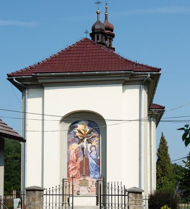 Zdjęcie nr 11: Kościół murowany, składa się z nawy i zwróconego na południe prezbiterium, do którego przylega zakrystia, nad którą znajduje się skarbiec; od północy wieża. Prezbiterium jest węższe od nawy, o zaokrąglonych narożach, oddzielone od prostokątnej nawy łukiem tęczowym. Ściany kościoła gładkie, przeprute półkolistymi oknami – dwoma w prezbiterium, sześcioma w nawie. Od zachodu chór wsparty na dwóch kolumnach, z balustradą wyłamaną na środku, dekorowaną u spodu lambrekinem. Ściany kościoła gładkie, w dolnej partii osłonięte drewnianą boazerią, z wnęką na chrzcielnicę po lewej i drugą na drzwi z prawej strony. Wnętrze przekrywają stropy – zwierciadlany w prezbiterium i płaski  z fasetami w nawie. Na nich oraz w górnej partii ścian polichromia. Nad prezbiterium wizerunek zmartwychwstałego Chrystusa, nad nawą zakomponowana w kole scena adoracji Najświętszej Marii Panny przez apostołów, poniżej, na ścianach medaliony z postaciami ważnych osobistości, świętych i aniołów. Główne drzwi od północy, boczne od zachodu. 
Kościół posadowiony na cokole. Elewacja frontowa ze zdwojonym ryzalitem, którego środek odpowiada szerokości wieży; podziały poziome przeprowadzone przy pomocy gzymsów. Na osi wejście i  okno, oba w boniowanym obramieniu. Okno ujmuje polichromowana scena Zwiastowania. Ryzalit wieńczy trójkątny fronton. Cofnięty ryzalit w dolnej partii boniowany, wyżej gładki, zwieńczony ćwierćkolistymi fragmentami przerwanego przyczółka. Boki elewacji frontowej gładkie, zwieńczone frontonem przerwanym na masyw czworobocznej wieży przeprutej z każdej strony oknem w kształcie stojącego prostokąta zamkniętego łukiem pełnym. Elewacje boczne gładkie, przeprute półkolistymi oknami. Od wschodu poniżej okien szare płyciny, od południa, w kapliczkowej oprawie grupa Ukrzyżowania. Dach nad nawą dwuspadowy, nad prezbiterium trójspadowy, dach wieńczy baniasty hełm z latarnią zakończony krzyżem, na kalenicy barokowa wieżyczka na sygnaturkę. 
