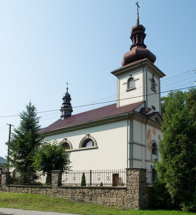 Zdjęcie nr 2: Kościół murowany, składa się z nawy i zwróconego na południe prezbiterium, do którego przylega zakrystia, nad którą znajduje się skarbiec; od północy wieża. Prezbiterium jest węższe od nawy, o zaokrąglonych narożach, oddzielone od prostokątnej nawy łukiem tęczowym. Ściany kościoła gładkie, przeprute półkolistymi oknami – dwoma w prezbiterium, sześcioma w nawie. Od zachodu chór wsparty na dwóch kolumnach, z balustradą wyłamaną na środku, dekorowaną u spodu lambrekinem. Ściany kościoła gładkie, w dolnej partii osłonięte drewnianą boazerią, z wnęką na chrzcielnicę po lewej i drugą na drzwi z prawej strony. Wnętrze przekrywają stropy – zwierciadlany w prezbiterium i płaski  z fasetami w nawie. Na nich oraz w górnej partii ścian polichromia. Nad prezbiterium wizerunek zmartwychwstałego Chrystusa, nad nawą zakomponowana w kole scena adoracji Najświętszej Marii Panny przez apostołów, poniżej, na ścianach medaliony z postaciami ważnych osobistości, świętych i aniołów. Główne drzwi od północy, boczne od zachodu. 
Kościół posadowiony na cokole. Elewacja frontowa ze zdwojonym ryzalitem, którego środek odpowiada szerokości wieży; podziały poziome przeprowadzone przy pomocy gzymsów. Na osi wejście i  okno, oba w boniowanym obramieniu. Okno ujmuje polichromowana scena Zwiastowania. Ryzalit wieńczy trójkątny fronton. Cofnięty ryzalit w dolnej partii boniowany, wyżej gładki, zwieńczony ćwierćkolistymi fragmentami przerwanego przyczółka. Boki elewacji frontowej gładkie, zwieńczone frontonem przerwanym na masyw czworobocznej wieży przeprutej z każdej strony oknem w kształcie stojącego prostokąta zamkniętego łukiem pełnym. Elewacje boczne gładkie, przeprute półkolistymi oknami. Od wschodu poniżej okien szare płyciny, od południa, w kapliczkowej oprawie grupa Ukrzyżowania. Dach nad nawą dwuspadowy, nad prezbiterium trójspadowy, dach wieńczy baniasty hełm z latarnią zakończony krzyżem, na kalenicy barokowa wieżyczka na sygnaturkę. 
