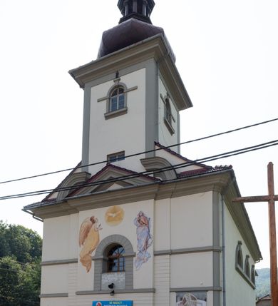 Zdjęcie nr 8: Kościół murowany, składa się z nawy i zwróconego na południe prezbiterium, do którego przylega zakrystia, nad którą znajduje się skarbiec; od północy wieża. Prezbiterium jest węższe od nawy, o zaokrąglonych narożach, oddzielone od prostokątnej nawy łukiem tęczowym. Ściany kościoła gładkie, przeprute półkolistymi oknami – dwoma w prezbiterium, sześcioma w nawie. Od zachodu chór wsparty na dwóch kolumnach, z balustradą wyłamaną na środku, dekorowaną u spodu lambrekinem. Ściany kościoła gładkie, w dolnej partii osłonięte drewnianą boazerią, z wnęką na chrzcielnicę po lewej i drugą na drzwi z prawej strony. Wnętrze przekrywają stropy – zwierciadlany w prezbiterium i płaski  z fasetami w nawie. Na nich oraz w górnej partii ścian polichromia. Nad prezbiterium wizerunek zmartwychwstałego Chrystusa, nad nawą zakomponowana w kole scena adoracji Najświętszej Marii Panny przez apostołów, poniżej, na ścianach medaliony z postaciami ważnych osobistości, świętych i aniołów. Główne drzwi od północy, boczne od zachodu. 
Kościół posadowiony na cokole. Elewacja frontowa ze zdwojonym ryzalitem, którego środek odpowiada szerokości wieży; podziały poziome przeprowadzone przy pomocy gzymsów. Na osi wejście i  okno, oba w boniowanym obramieniu. Okno ujmuje polichromowana scena Zwiastowania. Ryzalit wieńczy trójkątny fronton. Cofnięty ryzalit w dolnej partii boniowany, wyżej gładki, zwieńczony ćwierćkolistymi fragmentami przerwanego przyczółka. Boki elewacji frontowej gładkie, zwieńczone frontonem przerwanym na masyw czworobocznej wieży przeprutej z każdej strony oknem w kształcie stojącego prostokąta zamkniętego łukiem pełnym. Elewacje boczne gładkie, przeprute półkolistymi oknami. Od wschodu poniżej okien szare płyciny, od południa, w kapliczkowej oprawie grupa Ukrzyżowania. Dach nad nawą dwuspadowy, nad prezbiterium trójspadowy, dach wieńczy baniasty hełm z latarnią zakończony krzyżem, na kalenicy barokowa wieżyczka na sygnaturkę. 

