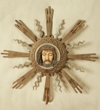 Zdjęcie nr 1: Okrągły medalion ujęty opaską z motywem korony cierniowej 
oraz profilowanym pasem; wewnątrz płaskorzeźbiony wizerunek Chrystusa. Twarz ma trójkątną, o dużych, migdałowatych, zamkniętych oczach, prostym nosie, wąskich ustach; okoloną krótką, rozdwajającą się brodą oraz lekko kręconymi włosami. Na głowie ma koronę cierniową. Medalion ujęty motywem trójkątów oraz glorią złożoną z ułożonych naprzemiennie promieni strzępionych i falistych. Twarz Chrystusa polichromowana naturalistycznie z zaznaczonymi ranami na głowie; medalion i gloria złocone i srebrzone. Na odwrocie napis „Oblicze Pana Jezusa / Rzeźbił dnia 28/X. / w 1939 r. WGórka.”



