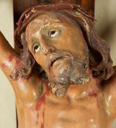 Zdjęcie nr 2: Krzyż o prostym zakończeniu ramion, na froncie u dołu ryty krzyż jerozolimski, na skrzyżowaniu ramion napis „Jerusalem”. 
Figura żywego Chrystusa przymocowana do krzyża trzema gwoździami. Ciało w dużym zwisie, o wysoko uniesionych  ramionach układających się na kształt litery „V”, o esowato wygiętej sylwetce, z uniesioną głową skierowaną w lewo, nogi ugięte w kolanach, stopy skrzyżowane w układzie prawa na lewą. Twarz ma szczupłą, o oczach skierowanych w górę, prostym nosie i otwartych ustach; okoloną krótką, rozdwojoną brodą oraz kręconymi włosami opadającymi na ramiona. Na głowie ma koronę cierniową. Ciało Chrystusa szczupłe i smukłe, o podkreślonych żebrach klatki piersiowej. Przez biodra ma przewiązane białe perizonium, ściśle przylegające do ciała, silnie drapowane, ze zwisem tkaniny zawiniętym na prawym udzie. Polichromia ciała naturalistyczna, z zaznaczonymi śladami męki; oczy ma emaliowane. 






