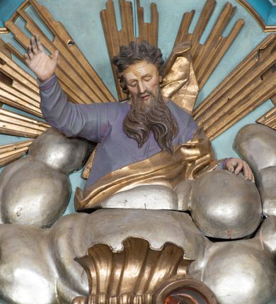 Zdjęcie nr 15: Nastawa ołtarzowa architektoniczna, jednoosiowa, jednokondygnacyjna ze zwieńczeniem, ustawiona na dwustrefowym cokole, z wyodrębnionymi dwiema parami prostopadłościanów. Ołtarz kamienny, wolnostojący, ustawiony na dwustopniowej podstawie, ujęty po bokach fryzowanymi konsolami. Mensa kamienna z marmurowym portatylem. Na przedniej ściance wyrzeźbiona w licu płycina, ujęta kanelowanymi lizenami, z monogramem IHS w polu. Na ołtarzu ustawione tabernakulum z tronem wystawienia. Tabernakulum w formie drewnianej skrzynki z obitymi blachą prostokątnymi drzwiczkami, ujętymi ramą. W ich polu medalion z przedstawieniem pelikana karmiącego młode na tle krzyża. Tron wystawienia w formie obrotowej, trójdzielnej niszy o wykroju stojącego prostokąta zamkniętego stylizowanym łukiem półokrągłym, zwieńczonej gzymsem. Nisza flankowana dekoracją w postaci liści ostrokrzewu i kampanuli, na gzymsie rocaille. Tabernakulum i tron ujęte parą niższych kolumn o kapitelach kompozytowych, na wysokich cokołach, dźwigających imposty, na których stoją wazony oraz spływami zakończonymi cokołami z fragmentami przerwanego przyczółka, na których klęczą adorujące anioły. Spływy dekorowane rocaille'em z podwieszonymi kampanulami. Kondygnacja ujęta dwiema parami pilastrów i stojących przed nimi kolumn o kapitelach kompozytowych, ustawionymi delikatnie pod kątem względem lica, wewnętrzna para wysunięta do przodu. Po wewnętrznej stronie ołtarza para pilastrów, których konsole podtrzymują belkowanie, a trzony dekorowane są zwisami roślinnymi, na ich tle figury św. Joachima i św. Anny. Podpory dźwigają pełne belkowanie, wyłamane na ich osi, przerwane nad polem środkowym oraz fragmenty przerwanego, falistego przyczółka z siedzącymi puttami, a także wolutowe cokoły z wazonami na zewnętrznych krawędziach belkowania. Fryz dekorowany rozetami. W polu środkowym nisza w formie stojącego prostokąta zamkniętego łukiem półkolistym nadwieszonym, ujęta profilowaną ramą z mniejszym obrazem Matki Boskiej z Dzieciątkiem oraz przedstawieniem św. Klemensa na zasuwie. Powyżej rokokowy kartusz z monogramem Marii, na którym dwa putta trzymają koronę, z podwieszonymi zwisami kwiatowymi, ujmującymi ramę pola głównego poniżej. Zwieńczenie w formie stojącego prostokąta z wolutowymi uszakami, zamkniętego gzymsem w formie łuku odcinkowego nadwieszonego. W polu rzeźbiarskie przedstawienie półpostaci Boga Ojca pośród obłoków, na tle glorii promienistej, ujętego przez siedzące na gzymsie, adorujące aniołki. Ołtarz flankują umocowane do ścian konsole z figurami św. Piotra i św. Pawła. Struktura w całości polichromowana w kolorze jasnoniebieskim, z niebieskimi i bladoróżowymi detalami, kolumny, profile i ornamentyka złocone, detale srebrzone.  
