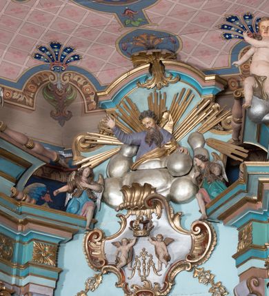 Zdjęcie nr 10: Nastawa ołtarzowa architektoniczna, jednoosiowa, jednokondygnacyjna ze zwieńczeniem, ustawiona na dwustrefowym cokole, z wyodrębnionymi dwiema parami prostopadłościanów. Ołtarz kamienny, wolnostojący, ustawiony na dwustopniowej podstawie, ujęty po bokach fryzowanymi konsolami. Mensa kamienna z marmurowym portatylem. Na przedniej ściance wyrzeźbiona w licu płycina, ujęta kanelowanymi lizenami, z monogramem IHS w polu. Na ołtarzu ustawione tabernakulum z tronem wystawienia. Tabernakulum w formie drewnianej skrzynki z obitymi blachą prostokątnymi drzwiczkami, ujętymi ramą. W ich polu medalion z przedstawieniem pelikana karmiącego młode na tle krzyża. Tron wystawienia w formie obrotowej, trójdzielnej niszy o wykroju stojącego prostokąta zamkniętego stylizowanym łukiem półokrągłym, zwieńczonej gzymsem. Nisza flankowana dekoracją w postaci liści ostrokrzewu i kampanuli, na gzymsie rocaille. Tabernakulum i tron ujęte parą niższych kolumn o kapitelach kompozytowych, na wysokich cokołach, dźwigających imposty, na których stoją wazony oraz spływami zakończonymi cokołami z fragmentami przerwanego przyczółka, na których klęczą adorujące anioły. Spływy dekorowane rocaille'em z podwieszonymi kampanulami. Kondygnacja ujęta dwiema parami pilastrów i stojących przed nimi kolumn o kapitelach kompozytowych, ustawionymi delikatnie pod kątem względem lica, wewnętrzna para wysunięta do przodu. Po wewnętrznej stronie ołtarza para pilastrów, których konsole podtrzymują belkowanie, a trzony dekorowane są zwisami roślinnymi, na ich tle figury św. Joachima i św. Anny. Podpory dźwigają pełne belkowanie, wyłamane na ich osi, przerwane nad polem środkowym oraz fragmenty przerwanego, falistego przyczółka z siedzącymi puttami, a także wolutowe cokoły z wazonami na zewnętrznych krawędziach belkowania. Fryz dekorowany rozetami. W polu środkowym nisza w formie stojącego prostokąta zamkniętego łukiem półkolistym nadwieszonym, ujęta profilowaną ramą z mniejszym obrazem Matki Boskiej z Dzieciątkiem oraz przedstawieniem św. Klemensa na zasuwie. Powyżej rokokowy kartusz z monogramem Marii, na którym dwa putta trzymają koronę, z podwieszonymi zwisami kwiatowymi, ujmującymi ramę pola głównego poniżej. Zwieńczenie w formie stojącego prostokąta z wolutowymi uszakami, zamkniętego gzymsem w formie łuku odcinkowego nadwieszonego. W polu rzeźbiarskie przedstawienie półpostaci Boga Ojca pośród obłoków, na tle glorii promienistej, ujętego przez siedzące na gzymsie, adorujące aniołki. Ołtarz flankują umocowane do ścian konsole z figurami św. Piotra i św. Pawła. Struktura w całości polichromowana w kolorze jasnoniebieskim, z niebieskimi i bladoróżowymi detalami, kolumny, profile i ornamentyka złocone, detale srebrzone.  
