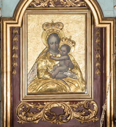 Zdjęcie nr 5: Nastawa ołtarzowa architektoniczna, jednoosiowa, jednokondygnacyjna ze zwieńczeniem, ustawiona na dwustrefowym cokole, z wyodrębnionymi dwiema parami prostopadłościanów. Ołtarz kamienny, wolnostojący, ustawiony na dwustopniowej podstawie, ujęty po bokach fryzowanymi konsolami. Mensa kamienna z marmurowym portatylem. Na przedniej ściance wyrzeźbiona w licu płycina, ujęta kanelowanymi lizenami, z monogramem IHS w polu. Na ołtarzu ustawione tabernakulum z tronem wystawienia. Tabernakulum w formie drewnianej skrzynki z obitymi blachą prostokątnymi drzwiczkami, ujętymi ramą. W ich polu medalion z przedstawieniem pelikana karmiącego młode na tle krzyża. Tron wystawienia w formie obrotowej, trójdzielnej niszy o wykroju stojącego prostokąta zamkniętego stylizowanym łukiem półokrągłym, zwieńczonej gzymsem. Nisza flankowana dekoracją w postaci liści ostrokrzewu i kampanuli, na gzymsie rocaille. Tabernakulum i tron ujęte parą niższych kolumn o kapitelach kompozytowych, na wysokich cokołach, dźwigających imposty, na których stoją wazony oraz spływami zakończonymi cokołami z fragmentami przerwanego przyczółka, na których klęczą adorujące anioły. Spływy dekorowane rocaille'em z podwieszonymi kampanulami. Kondygnacja ujęta dwiema parami pilastrów i stojących przed nimi kolumn o kapitelach kompozytowych, ustawionymi delikatnie pod kątem względem lica, wewnętrzna para wysunięta do przodu. Po wewnętrznej stronie ołtarza para pilastrów, których konsole podtrzymują belkowanie, a trzony dekorowane są zwisami roślinnymi, na ich tle figury św. Joachima i św. Anny. Podpory dźwigają pełne belkowanie, wyłamane na ich osi, przerwane nad polem środkowym oraz fragmenty przerwanego, falistego przyczółka z siedzącymi puttami, a także wolutowe cokoły z wazonami na zewnętrznych krawędziach belkowania. Fryz dekorowany rozetami. W polu środkowym nisza w formie stojącego prostokąta zamkniętego łukiem półkolistym nadwieszonym, ujęta profilowaną ramą z mniejszym obrazem Matki Boskiej z Dzieciątkiem oraz przedstawieniem św. Klemensa na zasuwie. Powyżej rokokowy kartusz z monogramem Marii, na którym dwa putta trzymają koronę, z podwieszonymi zwisami kwiatowymi, ujmującymi ramę pola głównego poniżej. Zwieńczenie w formie stojącego prostokąta z wolutowymi uszakami, zamkniętego gzymsem w formie łuku odcinkowego nadwieszonego. W polu rzeźbiarskie przedstawienie półpostaci Boga Ojca pośród obłoków, na tle glorii promienistej, ujętego przez siedzące na gzymsie, adorujące aniołki. Ołtarz flankują umocowane do ścian konsole z figurami św. Piotra i św. Pawła. Struktura w całości polichromowana w kolorze jasnoniebieskim, z niebieskimi i bladoróżowymi detalami, kolumny, profile i ornamentyka złocone, detale srebrzone.  
