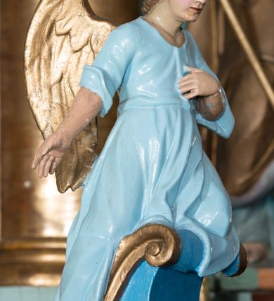 Zdjęcie nr 36: Nastawa ołtarzowa architektoniczna, jednoosiowa, jednokondygnacyjna ze zwieńczeniem, ustawiona na dwustrefowym cokole, z wyodrębnionymi dwiema parami prostopadłościanów. Ołtarz kamienny, wolnostojący, ustawiony na dwustopniowej podstawie, ujęty po bokach fryzowanymi konsolami. Mensa kamienna z marmurowym portatylem. Na przedniej ściance wyrzeźbiona w licu płycina, ujęta kanelowanymi lizenami, z monogramem IHS w polu. Na ołtarzu ustawione tabernakulum z tronem wystawienia. Tabernakulum w formie drewnianej skrzynki z obitymi blachą prostokątnymi drzwiczkami, ujętymi ramą. W ich polu medalion z przedstawieniem pelikana karmiącego młode na tle krzyża. Tron wystawienia w formie obrotowej, trójdzielnej niszy o wykroju stojącego prostokąta zamkniętego stylizowanym łukiem półokrągłym, zwieńczonej gzymsem. Nisza flankowana dekoracją w postaci liści ostrokrzewu i kampanuli, na gzymsie rocaille. Tabernakulum i tron ujęte parą niższych kolumn o kapitelach kompozytowych, na wysokich cokołach, dźwigających imposty, na których stoją wazony oraz spływami zakończonymi cokołami z fragmentami przerwanego przyczółka, na których klęczą adorujące anioły. Spływy dekorowane rocaille'em z podwieszonymi kampanulami. Kondygnacja ujęta dwiema parami pilastrów i stojących przed nimi kolumn o kapitelach kompozytowych, ustawionymi delikatnie pod kątem względem lica, wewnętrzna para wysunięta do przodu. Po wewnętrznej stronie ołtarza para pilastrów, których konsole podtrzymują belkowanie, a trzony dekorowane są zwisami roślinnymi, na ich tle figury św. Joachima i św. Anny. Podpory dźwigają pełne belkowanie, wyłamane na ich osi, przerwane nad polem środkowym oraz fragmenty przerwanego, falistego przyczółka z siedzącymi puttami, a także wolutowe cokoły z wazonami na zewnętrznych krawędziach belkowania. Fryz dekorowany rozetami. W polu środkowym nisza w formie stojącego prostokąta zamkniętego łukiem półkolistym nadwieszonym, ujęta profilowaną ramą z mniejszym obrazem Matki Boskiej z Dzieciątkiem oraz przedstawieniem św. Klemensa na zasuwie. Powyżej rokokowy kartusz z monogramem Marii, na którym dwa putta trzymają koronę, z podwieszonymi zwisami kwiatowymi, ujmującymi ramę pola głównego poniżej. Zwieńczenie w formie stojącego prostokąta z wolutowymi uszakami, zamkniętego gzymsem w formie łuku odcinkowego nadwieszonego. W polu rzeźbiarskie przedstawienie półpostaci Boga Ojca pośród obłoków, na tle glorii promienistej, ujętego przez siedzące na gzymsie, adorujące aniołki. Ołtarz flankują umocowane do ścian konsole z figurami św. Piotra i św. Pawła. Struktura w całości polichromowana w kolorze jasnoniebieskim, z niebieskimi i bladoróżowymi detalami, kolumny, profile i ornamentyka złocone, detale srebrzone.  
