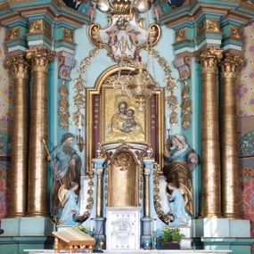 Zdjęcie nr 1: Nastawa ołtarzowa architektoniczna, jednoosiowa, jednokondygnacyjna ze zwieńczeniem, ustawiona na dwustrefowym cokole, z wyodrębnionymi dwiema parami prostopadłościanów. Ołtarz kamienny, wolnostojący, ustawiony na dwustopniowej podstawie, ujęty po bokach fryzowanymi konsolami. Mensa kamienna z marmurowym portatylem. Na przedniej ściance wyrzeźbiona w licu płycina, ujęta kanelowanymi lizenami, z monogramem IHS w polu. Na ołtarzu ustawione tabernakulum z tronem wystawienia. Tabernakulum w formie drewnianej skrzynki z obitymi blachą prostokątnymi drzwiczkami, ujętymi ramą. W ich polu medalion z przedstawieniem pelikana karmiącego młode na tle krzyża. Tron wystawienia w formie obrotowej, trójdzielnej niszy o wykroju stojącego prostokąta zamkniętego stylizowanym łukiem półokrągłym, zwieńczonej gzymsem. Nisza flankowana dekoracją w postaci liści ostrokrzewu i kampanuli, na gzymsie rocaille. Tabernakulum i tron ujęte parą niższych kolumn o kapitelach kompozytowych, na wysokich cokołach, dźwigających imposty, na których stoją wazony oraz spływami zakończonymi cokołami z fragmentami przerwanego przyczółka, na których klęczą adorujące anioły. Spływy dekorowane rocaille'em z podwieszonymi kampanulami. Kondygnacja ujęta dwiema parami pilastrów i stojących przed nimi kolumn o kapitelach kompozytowych, ustawionymi delikatnie pod kątem względem lica, wewnętrzna para wysunięta do przodu. Po wewnętrznej stronie ołtarza para pilastrów, których konsole podtrzymują belkowanie, a trzony dekorowane są zwisami roślinnymi, na ich tle figury św. Joachima i św. Anny. Podpory dźwigają pełne belkowanie, wyłamane na ich osi, przerwane nad polem środkowym oraz fragmenty przerwanego, falistego przyczółka z siedzącymi puttami, a także wolutowe cokoły z wazonami na zewnętrznych krawędziach belkowania. Fryz dekorowany rozetami. W polu środkowym nisza w formie stojącego prostokąta zamkniętego łukiem półkolistym nadwieszonym, ujęta profilowaną ramą z mniejszym obrazem Matki Boskiej z Dzieciątkiem oraz przedstawieniem św. Klemensa na zasuwie. Powyżej rokokowy kartusz z monogramem Marii, na którym dwa putta trzymają koronę, z podwieszonymi zwisami kwiatowymi, ujmującymi ramę pola głównego poniżej. Zwieńczenie w formie stojącego prostokąta z wolutowymi uszakami, zamkniętego gzymsem w formie łuku odcinkowego nadwieszonego. W polu rzeźbiarskie przedstawienie półpostaci Boga Ojca pośród obłoków, na tle glorii promienistej, ujętego przez siedzące na gzymsie, adorujące aniołki. Ołtarz flankują umocowane do ścian konsole z figurami św. Piotra i św. Pawła. Struktura w całości polichromowana w kolorze jasnoniebieskim, z niebieskimi i bladoróżowymi detalami, kolumny, profile i ornamentyka złocone, detale srebrzone.  
