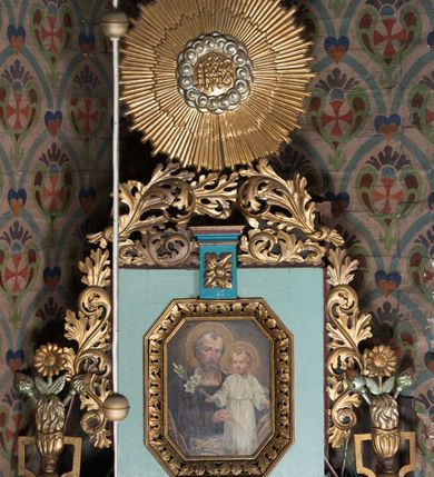 Zdjęcie nr 5: Nastawa ołtarzowa architektoniczna, jednoosiowa, jednokondygnacyjna ze zwieńczeniem ustawiona na cokole z wyodrębnionymi po bokach prostopadłościanami. Ołtarz kamienny prostopadłościenny, ujęty po bokach esownicami, z przodu flankowany kanelowanymi lizenami, w centrum płaskorzeźbione gorejące serce. Nastawa flankowana parą kolumn o kapitelach korynckich, dźwigających belkowanie wyłamane na ich osi, przerwane przez pole środkowe, w partii fryzu dekorowane rozetami. Całe pole środkowe wypełnia nisza w formie stojącego prostokąta z obrazem Matki Boskiej Różańcowej ze św. Dominikiem i św. Katarzyną Sieneńską, ujęta złoconą, profilowaną ramą. Na belkowaniu ustawione dwa wazony z bukietami kwiatów. Kondygnacja flankowana uszami utworzonymi z ażurowego akantu z kampanulami. Zwieńczenie w formie stojącego prostokąta zakończonego kluczem z rozetą, ujętego z trzech stron ażurowym akantem. W polu obraz św. Józefa z Dzieciątkiem w formie stojącego prostokąta o ściętych narożach, w ramie dekorowanej ażurowym ornamentem roślinnym. Całość zakończona medalionem z monogramem Marii otoczonym obłokami, w glorii promienistej. Struktura polichromowana w kolorze jasnoniebieskim, z niebieskimi i czerwonymi detalami, kolumny, profile i ornamentyka złocone, elementy dekoracji srebrzone. 