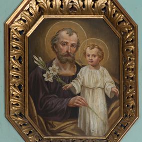 Zdjęcie nr 1: Obraz w formie stojącego prostokąta o ściętych narożach. W centrum św. Józef ukazany do pasa, z Dzieciątkiem w pozycji stojącej. Józef przedstawiony frontalnie z ugiętą z przodu prawą ręką, w której trzyma gałązkę lilii. Twarz ma szczupłą, o starczych rysach, dużych, okrągłych oczach, prostym nosie i pełnych ustach, okoloną krótką, siwą brodą i włosami. Ubrany jest w fioletową tunikę i jasnobrązowy płaszcz zawieszony przez lewe ramię, skumulowany w dolnej części obrazu. Dzieciątko ukazane frontalnie, z rękami rozłożonymi na boki. Twarz ma owalną, o pełnych policzkach, okrągłych oczach, małym nosie i pełnych ustach, okoloną jasnymi, krótkimi włosami. Ubrane jest w białą, luźną tunikę, przewiązaną w talii.  Józef i Dzieciątko wokół głów mają nimby. Postacie ukazane na cieniowanym, żółto-brązowym tle, rozjaśnionym wokół ich głów. 