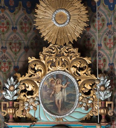 Zdjęcie nr 5: Nastawa ołtarzowa architektoniczna, jednoosiowa, jednokondygnacyjna ze zwieńczeniem ustawiona na cokole z wyodrębnionymi po bokach prostopadłościanami. Ołtarz kamienny prostopadłościenny, ujęty po bokach esownicami, z przodu flankowany kanelowanymi lizenami, w centrum krzyż. Nastawa flankowana parą kolumn o kapitelach kompozytowych, dźwigających pełne belkowanie wyłamane na ich osi, w partii fryzu dekorowane rozetami, wicią roślinną i muszlą. Całe pole środkowe wypełnia nisza w formie stojącego prostokąta z obrazem św. Wojciecha, ujęta złoconą ramą zdobioną dekoracją roślinną. Na belkowaniu ustawione dwa wazony z bukietami kwiatów. Kondygnacja flankowana uszami utworzonymi z ażurowego akantu. Zwieńczenie w formie owalnego pola z obrazem Męczeństwa św. Sebastiana ujętego wieńcem laurowym i ażurowymi liśćmi akantu, u dołu dwa rogi obfitości. Całość zakończona medalionem z okiem Opatrzności w glorii promienistej. Struktura polichromowana w kolorze jasnoniebieskim, z niebieskimi i czerwonymi detalami, kolumny, profile i ornamentyka złocone, elementy dekoracji srebrzone. 