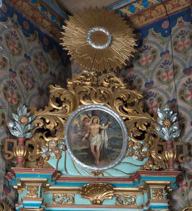 Zdjęcie nr 6: Nastawa ołtarzowa architektoniczna, jednoosiowa, jednokondygnacyjna ze zwieńczeniem ustawiona na cokole z wyodrębnionymi po bokach prostopadłościanami. Ołtarz kamienny prostopadłościenny, ujęty po bokach esownicami, z przodu flankowany kanelowanymi lizenami, w centrum krzyż. Nastawa flankowana parą kolumn o kapitelach kompozytowych, dźwigających pełne belkowanie wyłamane na ich osi, w partii fryzu dekorowane rozetami, wicią roślinną i muszlą. Całe pole środkowe wypełnia nisza w formie stojącego prostokąta z obrazem św. Wojciecha, ujęta złoconą ramą zdobioną dekoracją roślinną. Na belkowaniu ustawione dwa wazony z bukietami kwiatów. Kondygnacja flankowana uszami utworzonymi z ażurowego akantu. Zwieńczenie w formie owalnego pola z obrazem Męczeństwa św. Sebastiana ujętego wieńcem laurowym i ażurowymi liśćmi akantu, u dołu dwa rogi obfitości. Całość zakończona medalionem z okiem Opatrzności w glorii promienistej. Struktura polichromowana w kolorze jasnoniebieskim, z niebieskimi i czerwonymi detalami, kolumny, profile i ornamentyka złocone, elementy dekoracji srebrzone. 