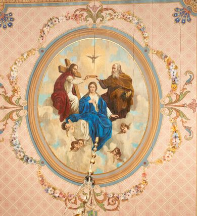 Zdjęcie nr 1: W prezbiterium w dolnej połowie ścian polichromia w formie namalowanej jasnoczerwonej, wielkowzorzytej tkaniny o motywach geometrycznych i roślinnych z niebieskim monogramem Marii i żółtymi koronami; jej górny brzeg odwiedziony jest pasem z brązowo-czerwoną dekoracją roślinną. Ściana przedzielona w połowie wysokości pasem z arkadkami wypełnionymi żółtymi wazonami oraz dekoracją roślinną na zielonym tle. W ich przyłuczach czerwone pola wypełnione malowaną roślinnością. W górnej połowie ścian malowane płyciny o jasnobrązowych ramach, których pola wypełnione są wzorem o motywie żółtych sześcioboków z fioletowymi kwiatami. Na południowej ścianie prezbiterium okna obwiedzione malowanymi, mazerowanymi ramami. W górnej części ściany, pod belkowaniem fryz utworzony z uskrzydlonych główek anielskich ukazanych na niebieskim tle, pomiędzy którymi znajdują się czerwone kampanule, pod nim podwieszone kwiatowe girlandy. Ściany zakończone profilowanym gzymsem, pomalowanym w dwa pasy – czerwony i niebieski, dekorowane motywem liści. Ściany podzielone lizenami w kolorze fioletowym, zdobionymi motywami geometrycznymi, różnymi w dolnej i górnej połowie. Strop prezbiterium z namalowaną płyciną w formie stojącego prostokąta, zamkniętego u dołu trójbocznie, o wklęsłych sześciu narożach, w których namalowana jest dekoracja roślinna. Płycina ujęta brązowo-żółtą ramą zdobioną motywem roślinnym oraz niebieskim pasem, z abstrakcyjnym motywem na wklęśnięciach. Różowe pole wypełnione białą kratką z kwiatami. W jego centrum owalny medalion w malowanej, profilowanej ramie oraz niebieskiej opasce z wypustkami, na których zawieszonych jest wokół osiem kwiatowych girland oraz cztery fantazyjne motywy kwiatowe. W medalionie namalowana scena Koronacji Matki Bożej. W jego centrum siedząca na obłokach Maria, ukazana frontalnie, z prawą ręką złożoną na piersi, lewą wyciągniętą w bok. Twarz ma pociągłą, o migdałowatych oczach, prostym nosie i pełnych ustach, okoloną długimi, falowanymi, jasnymi włosami. Ubrana jest w białą tunikę i niebieski płaszcz zarzucony na ramiona i kolana. Po jej prawej siedzi Chrystus, zwrócony w trzech czwartych w lewo, pochylony, prawą ręką podtrzymuje nad jej głową koronę. Twarz ma podłużną, o okrągłych oczach, lekko garbatym nosie i pełnych ustach, okolona brązowymi włosami i brodą. Ubrany jest w białą tunikę i czerwony płaszcz, o jego lewe ramię oparty jest krzyż. Po lewej stronie Marii siedzi Bóg Ojciec, zwrócony w trzech czwartych w prawo, lewą ręką przytrzymuje przy boku kulę, prawą podtrzymuje koronę nad głową Marii. Bóg ukazany jako starzec, o wysokim czole, podłużnej twarzy, małych oczach, garbatym nosie i pełnych ustach. Włosy i brodę ma długie i siwe. Ubrany jest w fioletową tunikę i jasnobrązowy płaszcz. Nad postaciami unosi się gołębica Ducha Świętego w glorii promienistej. Scena ukazana na tle błękitnego nieba, wypełnionego obłokami, w dolnej części obrazu z ukazanymi uskrzydlonymi główkami anielskimi. 
Ściany nawy w jednej trzeciej wysokości obwiedzione są pasem z malowanymi czerwono-brązowymi płycinami o naprzemiennym układzie owali i rombów, wypełnionymi dekoracją geometryczną i motywami roślinnymi. Ponad nimi wzdłuż ściany malowany niebieski pas o kolorowej i fantazyjnej dekoracji. Ściany w dwóch trzecich wysokości pokryte jasnoróżową polichromią o wielobarwnym, fantazyjnym, geometryczno-roślinnym wzorze z motywem równoramiennych krzyży. Ściany zakończone niebieskim fryzem przypominającym lambrekin z motywami geometrycznymi. Całość opasana profilowanym gzymsem, pomalowanym w dwa pasy – czerwony i niebieski, z dekoracją o motywach liści. Ściany podzielone lizenami pomalowanymi na kolor fioletowy, z dekoracją geometryczną. Na ścianach północnej i południowej po dwa okna obwiedzione malowanymi, mazerowanymi ramami. Pomiędzy oknami sceny w formie stojącego prostokąta zamkniętego łukiem półkolistym, w malowanej ramie dekorowanej cekinami. U dołu ramy fragment gzymsu dekorowanego kimationem z podwieszeniem zdobionym uskrzydloną główką anielską i meandrem. Rama zamknięta gzymsem wyłamanym na kształt łuku odcinkowego, podtrzymywanym na konsolach, dekorowanych motywem roślinnym. 
Na ścianie północnej scena z przedstawieniem św. Jakuba Większego z aniołem. W dolnej części obrazu święty w pozycji półleżącej, oparty o schody, ukazany frontalnie, z uniesioną głową, skierowaną w lewo i skrzyżowanymi na piersi rekami. Twarz ma owalną, o dużych oczach skierowanych w górę, prostym nosie i rozchylonych ustach, okoloną, krótkimi, jasnobrązowymi włosami i brodą. Wokół jego głowy nimb. Ubrany jest w ciemnobrązową tunikę, przepasaną sznurem, na lewym ramieniu ma muszlę, lewą ręką przytrzymuje laskę z bukłakiem. Na stopach ma sandały. Nad świętym unosi się anioł, zwrócony w trzech czwartych w lewo, w wykroku, z pochyloną głową, w prawej ręce trzyma liść palmy, w lewej, nad głową świętego - wieniec z róż. Anioł o młodzieńczej twarzy, z dużymi oczami zwróconymi w dół, dużym nosem i małymi ustami, okolonej jasnymi włosami sięgającymi ramion. Ubrany jest w żółtą tunikę oraz jasnofioletowy płaszcz. Ma białe i rozłożone skrzydła. Ukazany jest w otoczeniu obłoków. Poniżej, obok świętego na ziemi leży puklerz i miecz. Postacie ukazane we wnętrzu, z widoczną murowaną ścianą z oknami, fragmentem kolumny i schodami. W prawym dolnym sygnatura „M. Szczurowsk[i]”. 
Na ścianie południowej scena z przedstawieniem św. Izydora Oracza modlącego się przed kapliczką. W dolnej części obrazu święty w pozycji klęczącej, zwrócony profilem w prawo, z uniesionymi rękami o splecionych dłoniach w geście modlitwy, z uniesioną głową. Twarz ma szczupłą, o oczach skierowanych w górę, małym nosie i pełnych ustach, okoloną krótkimi, brązowymi włosami. Ubrany jest w białą koszulę, niebieski kaftan z czerwoną podszewką, przepasany w talii, z zawieszonym kluczem, na stopach ma buty. Przed nim, na ziemi leżą słomkowy kapelusz i bat. Przed świętym kapliczka w formie kamiennego krucyfiksu na cokole, pośród krzaków z kwiatami. Święty ukazany na tle pejzażu, z widocznym w oddali polem, na którym dwa woły ciągną pług, prowadzony przez anioła. Powyżej błękitne niebo zasnute ciemnymi chmurami, spod których wydobywa się strumień światła. W prawym dolnym rogu sygnatura „M. Szczurowski”. 
W zachodniej części nawy beżowa balustrada chóru muzycznego, na której namalowane są prostokątne płyciny, o krótszych bokach dekorowanych motywem roślinnym. Ich pola wypełnia niebieska opaska oraz różowa kratka ze zdobieniem roślinnym. Płycina środkowa w formie owalu z przedstawieniem Dawida, siedzącego na tronie i grającego na harfie. Postać ukazana do połowy, zwrócona w trzech czwartych w prawo, dwiema wyciągniętymi rękami dotyka strun harfy. Dawid o pociągłej twarzy, ze schematycznie oddanymi rysami, okolony brązowymi włosami i brodą. Na głowie ma koronę otwartą. Ubrany jest w czerwoną suknię, na ramiona ma narzuconą gronostajową pelerynę. Nad nim zawieszony czerwony baldachim, z zieloną podszewką. W oddali widoczny zarys zabudowań miejskich. Profile cokołu i gzymsu balustrady malowane w kolorowe pasy, z dekoracją roślinną. 
Na stropie nawy malowana płycina w formie stojącego prostokąta o zaokrąglonych narożach, ujęta niebieską ramą o geometrycznym wzorze, w miejscu naroży stylizowane roślinne palmety. W narożach płyciny cztery owalne medaliony z popiersiami św. Stanisława Kostki, św. Kazimierza Jagiellończyka, św. Stanisława z Piotrowinem i św. Jana Kantego. Medaliony ujęte są wolutowymi kartuszami, dekorowanymi stylizowanym ornamentem roślinnym. W polu centralnym malowanej płyciny scena ze św. Klemensem w formie stojącego prostokąta o wklęsłych narożach, ujęta malowaną ramą, w narożach uskrzydlone główki anielskie. Scena otoczona drugą ramą o fantazyjnym zarysie, dekorowaną na bokach fantazyjnymi szczytami z ornamentem roślinnym, które połączone są kwiecistymi girlandami z narożnymi kartuszami. Scena ze św. Klemensem przedstawia go w kamieniołomie, błogosławiącego robotników z kilofami. Święty ukazany jest jako starzec, z siwą brodą i włosami oraz łysiną na głowie. Ubrany jest w jasnofioletową sutannę, białą rokietę z dekoracyjnym obszyciem oraz jasnoczerwony, szeroki ornat, na piersi ma paliusz. W tle pomiędzy dwoma wzniesieniami skalnymi widoczne morze, z płynącym statkiem, w oddali zaś brzeg z domem. Na skarpie w lewej części obrazu ukazany baranek w glorii promienistej, na przeciwległej dwaj żołnierze, którzy zrzucili świętego z kotwicą zawieszoną u szyi do morza. Przy dolnej krawędzi obrazu sygnatura „pinxit 1910 / M. Szczurowski”.
