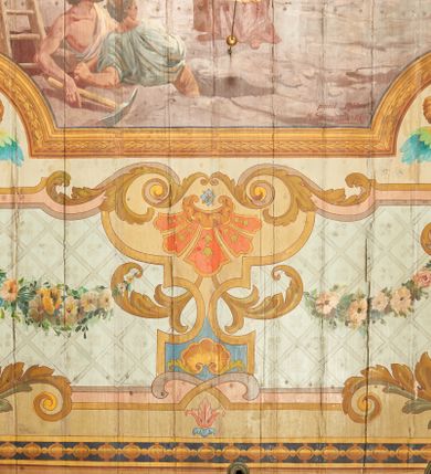 Zdjęcie nr 12: W prezbiterium w dolnej połowie ścian polichromia w formie namalowanej jasnoczerwonej, wielkowzorzytej tkaniny o motywach geometrycznych i roślinnych z niebieskim monogramem Marii i żółtymi koronami; jej górny brzeg odwiedziony jest pasem z brązowo-czerwoną dekoracją roślinną. Ściana przedzielona w połowie wysokości pasem z arkadkami wypełnionymi żółtymi wazonami oraz dekoracją roślinną na zielonym tle. W ich przyłuczach czerwone pola wypełnione malowaną roślinnością. W górnej połowie ścian malowane płyciny o jasnobrązowych ramach, których pola wypełnione są wzorem o motywie żółtych sześcioboków z fioletowymi kwiatami. Na południowej ścianie prezbiterium okna obwiedzione malowanymi, mazerowanymi ramami. W górnej części ściany, pod belkowaniem fryz utworzony z uskrzydlonych główek anielskich ukazanych na niebieskim tle, pomiędzy którymi znajdują się czerwone kampanule, pod nim podwieszone kwiatowe girlandy. Ściany zakończone profilowanym gzymsem, pomalowanym w dwa pasy – czerwony i niebieski, dekorowane motywem liści. Ściany podzielone lizenami w kolorze fioletowym, zdobionymi motywami geometrycznymi, różnymi w dolnej i górnej połowie. Strop prezbiterium z namalowaną płyciną w formie stojącego prostokąta, zamkniętego u dołu trójbocznie, o wklęsłych sześciu narożach, w których namalowana jest dekoracja roślinna. Płycina ujęta brązowo-żółtą ramą zdobioną motywem roślinnym oraz niebieskim pasem, z abstrakcyjnym motywem na wklęśnięciach. Różowe pole wypełnione białą kratką z kwiatami. W jego centrum owalny medalion w malowanej, profilowanej ramie oraz niebieskiej opasce z wypustkami, na których zawieszonych jest wokół osiem kwiatowych girland oraz cztery fantazyjne motywy kwiatowe. W medalionie namalowana scena Koronacji Matki Bożej. W jego centrum siedząca na obłokach Maria, ukazana frontalnie, z prawą ręką złożoną na piersi, lewą wyciągniętą w bok. Twarz ma pociągłą, o migdałowatych oczach, prostym nosie i pełnych ustach, okoloną długimi, falowanymi, jasnymi włosami. Ubrana jest w białą tunikę i niebieski płaszcz zarzucony na ramiona i kolana. Po jej prawej siedzi Chrystus, zwrócony w trzech czwartych w lewo, pochylony, prawą ręką podtrzymuje nad jej głową koronę. Twarz ma podłużną, o okrągłych oczach, lekko garbatym nosie i pełnych ustach, okolona brązowymi włosami i brodą. Ubrany jest w białą tunikę i czerwony płaszcz, o jego lewe ramię oparty jest krzyż. Po lewej stronie Marii siedzi Bóg Ojciec, zwrócony w trzech czwartych w prawo, lewą ręką przytrzymuje przy boku kulę, prawą podtrzymuje koronę nad głową Marii. Bóg ukazany jako starzec, o wysokim czole, podłużnej twarzy, małych oczach, garbatym nosie i pełnych ustach. Włosy i brodę ma długie i siwe. Ubrany jest w fioletową tunikę i jasnobrązowy płaszcz. Nad postaciami unosi się gołębica Ducha Świętego w glorii promienistej. Scena ukazana na tle błękitnego nieba, wypełnionego obłokami, w dolnej części obrazu z ukazanymi uskrzydlonymi główkami anielskimi. 
Ściany nawy w jednej trzeciej wysokości obwiedzione są pasem z malowanymi czerwono-brązowymi płycinami o naprzemiennym układzie owali i rombów, wypełnionymi dekoracją geometryczną i motywami roślinnymi. Ponad nimi wzdłuż ściany malowany niebieski pas o kolorowej i fantazyjnej dekoracji. Ściany w dwóch trzecich wysokości pokryte jasnoróżową polichromią o wielobarwnym, fantazyjnym, geometryczno-roślinnym wzorze z motywem równoramiennych krzyży. Ściany zakończone niebieskim fryzem przypominającym lambrekin z motywami geometrycznymi. Całość opasana profilowanym gzymsem, pomalowanym w dwa pasy – czerwony i niebieski, z dekoracją o motywach liści. Ściany podzielone lizenami pomalowanymi na kolor fioletowy, z dekoracją geometryczną. Na ścianach północnej i południowej po dwa okna obwiedzione malowanymi, mazerowanymi ramami. Pomiędzy oknami sceny w formie stojącego prostokąta zamkniętego łukiem półkolistym, w malowanej ramie dekorowanej cekinami. U dołu ramy fragment gzymsu dekorowanego kimationem z podwieszeniem zdobionym uskrzydloną główką anielską i meandrem. Rama zamknięta gzymsem wyłamanym na kształt łuku odcinkowego, podtrzymywanym na konsolach, dekorowanych motywem roślinnym. 
Na ścianie północnej scena z przedstawieniem św. Jakuba Większego z aniołem. W dolnej części obrazu święty w pozycji półleżącej, oparty o schody, ukazany frontalnie, z uniesioną głową, skierowaną w lewo i skrzyżowanymi na piersi rekami. Twarz ma owalną, o dużych oczach skierowanych w górę, prostym nosie i rozchylonych ustach, okoloną, krótkimi, jasnobrązowymi włosami i brodą. Wokół jego głowy nimb. Ubrany jest w ciemnobrązową tunikę, przepasaną sznurem, na lewym ramieniu ma muszlę, lewą ręką przytrzymuje laskę z bukłakiem. Na stopach ma sandały. Nad świętym unosi się anioł, zwrócony w trzech czwartych w lewo, w wykroku, z pochyloną głową, w prawej ręce trzyma liść palmy, w lewej, nad głową świętego - wieniec z róż. Anioł o młodzieńczej twarzy, z dużymi oczami zwróconymi w dół, dużym nosem i małymi ustami, okolonej jasnymi włosami sięgającymi ramion. Ubrany jest w żółtą tunikę oraz jasnofioletowy płaszcz. Ma białe i rozłożone skrzydła. Ukazany jest w otoczeniu obłoków. Poniżej, obok świętego na ziemi leży puklerz i miecz. Postacie ukazane we wnętrzu, z widoczną murowaną ścianą z oknami, fragmentem kolumny i schodami. W prawym dolnym sygnatura „M. Szczurowsk[i]”. 
Na ścianie południowej scena z przedstawieniem św. Izydora Oracza modlącego się przed kapliczką. W dolnej części obrazu święty w pozycji klęczącej, zwrócony profilem w prawo, z uniesionymi rękami o splecionych dłoniach w geście modlitwy, z uniesioną głową. Twarz ma szczupłą, o oczach skierowanych w górę, małym nosie i pełnych ustach, okoloną krótkimi, brązowymi włosami. Ubrany jest w białą koszulę, niebieski kaftan z czerwoną podszewką, przepasany w talii, z zawieszonym kluczem, na stopach ma buty. Przed nim, na ziemi leżą słomkowy kapelusz i bat. Przed świętym kapliczka w formie kamiennego krucyfiksu na cokole, pośród krzaków z kwiatami. Święty ukazany na tle pejzażu, z widocznym w oddali polem, na którym dwa woły ciągną pług, prowadzony przez anioła. Powyżej błękitne niebo zasnute ciemnymi chmurami, spod których wydobywa się strumień światła. W prawym dolnym rogu sygnatura „M. Szczurowski”. 
W zachodniej części nawy beżowa balustrada chóru muzycznego, na której namalowane są prostokątne płyciny, o krótszych bokach dekorowanych motywem roślinnym. Ich pola wypełnia niebieska opaska oraz różowa kratka ze zdobieniem roślinnym. Płycina środkowa w formie owalu z przedstawieniem Dawida, siedzącego na tronie i grającego na harfie. Postać ukazana do połowy, zwrócona w trzech czwartych w prawo, dwiema wyciągniętymi rękami dotyka strun harfy. Dawid o pociągłej twarzy, ze schematycznie oddanymi rysami, okolony brązowymi włosami i brodą. Na głowie ma koronę otwartą. Ubrany jest w czerwoną suknię, na ramiona ma narzuconą gronostajową pelerynę. Nad nim zawieszony czerwony baldachim, z zieloną podszewką. W oddali widoczny zarys zabudowań miejskich. Profile cokołu i gzymsu balustrady malowane w kolorowe pasy, z dekoracją roślinną. 
Na stropie nawy malowana płycina w formie stojącego prostokąta o zaokrąglonych narożach, ujęta niebieską ramą o geometrycznym wzorze, w miejscu naroży stylizowane roślinne palmety. W narożach płyciny cztery owalne medaliony z popiersiami św. Stanisława Kostki, św. Kazimierza Jagiellończyka, św. Stanisława z Piotrowinem i św. Jana Kantego. Medaliony ujęte są wolutowymi kartuszami, dekorowanymi stylizowanym ornamentem roślinnym. W polu centralnym malowanej płyciny scena ze św. Klemensem w formie stojącego prostokąta o wklęsłych narożach, ujęta malowaną ramą, w narożach uskrzydlone główki anielskie. Scena otoczona drugą ramą o fantazyjnym zarysie, dekorowaną na bokach fantazyjnymi szczytami z ornamentem roślinnym, które połączone są kwiecistymi girlandami z narożnymi kartuszami. Scena ze św. Klemensem przedstawia go w kamieniołomie, błogosławiącego robotników z kilofami. Święty ukazany jest jako starzec, z siwą brodą i włosami oraz łysiną na głowie. Ubrany jest w jasnofioletową sutannę, białą rokietę z dekoracyjnym obszyciem oraz jasnoczerwony, szeroki ornat, na piersi ma paliusz. W tle pomiędzy dwoma wzniesieniami skalnymi widoczne morze, z płynącym statkiem, w oddali zaś brzeg z domem. Na skarpie w lewej części obrazu ukazany baranek w glorii promienistej, na przeciwległej dwaj żołnierze, którzy zrzucili świętego z kotwicą zawieszoną u szyi do morza. Przy dolnej krawędzi obrazu sygnatura „pinxit 1910 / M. Szczurowski”.
