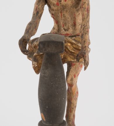 Zdjęcie nr 5: Pełnoplastyczna figurka Chrystusa z ruchomymi rękami, stojącego przy słupie ustawiona jest na owalnej podstawie. Chrystus stoi w wykroku, delikatnie pochylony ku słupowi, z głową skierowaną w prawo, z rękami wysuniętymi przed siebie, ujmującymi słup biczowania. Twarz ma szczupłą, pociągłą, o uwypuklonych kościach policzkowych, dużych oczach i nosie, okoloną krótką brodą i długimi, falowanymi włosami opadającymi na plecy. Ciało Chrystusa jest wychudzone, z silnie uwypuklonymi żebrami klatki piersiowej. Przez biodra ma przewiązane krótkie, obficie drapowane, złocone perizonium ze zwisem tkaniny na prawym boku. Słup w formie tralki na cokole. Polichromia ciała naturalistyczna, z zaznaczonymi licznymi strużkami krwi. 
