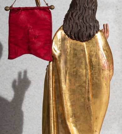 Zdjęcie nr 4: Figura pełnoplastyczna, ustawiona na rzeźbionym fragmencie podłoża i na niskiej podstawie na planie ośmioboku. Chrystus zwrócony jest frontalnie, z głową skierowaną w prawo. W lewej ręce trzyma drzewce zakończone krzyżem z chorągwią z tkaniny z naszytym krzyżem, prawą rękę unosi w geście błogosławieństwa. Twarz ma owalną, o dużych, półprzymkniętych oczach, uniesionych brwiach, dużym nosie i małych ustach, okoloną krótką brodą skręconą w dwa pukle oraz brązowymi włosami sięgającymi ramion, rzeźbionymi w regularne fale. Chrystus ubrany jest w złocony płaszcz z czerwoną podszewką zarzucony na ramiona i plecy, otaczający postać i zarzucony z przodu na lewe przedramię, odsłaniając nagi tors z zaznaczoną raną w boku. Polichromia ciała naturalistyczna.
