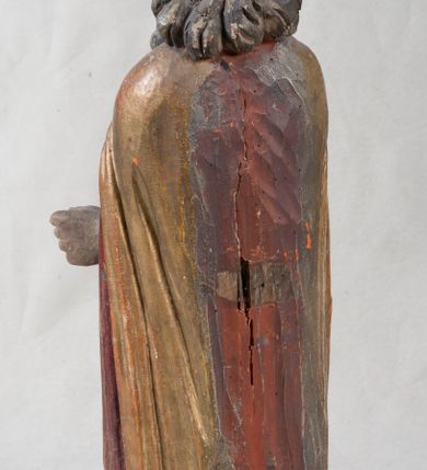 Zdjęcie nr 2: Rzeźba pełnoplastyczna, nieopracowana z tyłu, ustawiona na podstawie o nieregularnym kształcie. Święty zwrócony jest frontalnie, w delikatnym kontrapoście, z obiema rękami ugiętymi i wyciągniętymi do przodu. Prawa dłoń wysunięta zwrócona ku górze, w lewej trzyma laskę zakończoną krzyżem na kuli. Twarz ma kwadratową, o dużych oczach, krótkim nosie i małych, pełnych ustach, okoloną gęstą siwą brodą oraz falowanymi włosami, sięgającymi ramion. Mikołaj ubrany jest w długą, zieloną albę, niebieską rokietę zdobioną u dołu oraz zarzucony na ramiona, spięty na piersiach klamrą, pozłacany płaszcz, na głowie ma złoconą infułę. Polichromia ciała naturalistyczna, o jasnej, lekko zaróżowionej karnacji.
