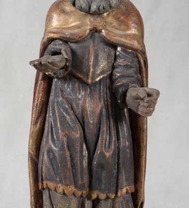 Zdjęcie nr 4: Rzeźba pełnoplastyczna, nieopracowana z tyłu, ustawiona na podstawie o nieregularnym kształcie. Święty zwrócony jest frontalnie, w delikatnym kontrapoście, z obiema rękami ugiętymi i wyciągniętymi do przodu. Prawa dłoń wysunięta zwrócona ku górze, w lewej trzyma laskę zakończoną krzyżem na kuli. Twarz ma kwadratową, o dużych oczach, krótkim nosie i małych, pełnych ustach, okoloną gęstą siwą brodą oraz falowanymi włosami, sięgającymi ramion. Mikołaj ubrany jest w długą, zieloną albę, niebieską rokietę zdobioną u dołu oraz zarzucony na ramiona, spięty na piersiach klamrą, pozłacany płaszcz, na głowie ma złoconą infułę. Polichromia ciała naturalistyczna, o jasnej, lekko zaróżowionej karnacji.
