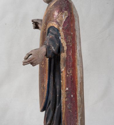 Zdjęcie nr 2: Rzeźba pełnoplastyczna, nieopracowana z tyłu, ustawiona jest na zielonej podstawie o nieregularnym kształcie. Święty zwrócony jest frontalnie, z obiema rękami ugiętymi, wyciągniętymi do przodu. Ma kwadratową twarz, o podkreślonej linii żuchwy i brody, o dużych oczach, krótkim nosie i małych, pełnych ustach. Włosy ma brązowe, falowane sięgające ramion. Ubrany jest w szarą, silnie drapowaną u dołu albę, widoczny u szyi humerał oraz złocony ornat skrzypcowy o wzorze kwiatowym, z pretekstą przednią w kolorze zielonym i niebieską podszewką. Na głowie ma złoconą mitrę. Polichromia ciała naturalistyczna o jasnej, zaróżowionej karnacji w partii twarzy.