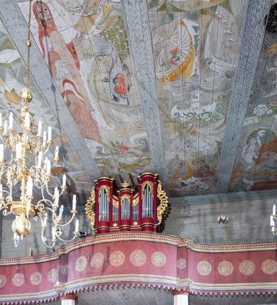 Zdjęcie nr 11: Kościół orientowany, drewniany o konstrukcji zrębowej z wieżą o konstrukcji słupowo-ryglowej na rzucie kwadratu. Nawa prostokątna z węższym, prostokątnym prezbiterium zamkniętym trójboczną absydą. Przy prezbiterium, od północy znajduje się zakrystia, a przy nawie, od południa – kruchta. Na osi nawy, od zachodu wieża o pochyłych ścianach z nadwieszoną izbicą. W kościele sześć otworów okiennych w kształcie stojących prostokątów, ujętych opaskami z prostych listew: dwa od strony północnej i cztery od strony południowej. Na zewnątrz okien zamontowane są współczesne kraty z ozdobnych prętów. Główne wejście do kościoła od zachodu w przyziemiu wieży. Dach dwuspadowy, od wschodu trójspadowy, wykonany w konstrukcji krokwiowo-jętkowej z podwójnymi jętkami, kryty gontem. Zakrystia zadaszona przedłużoną połacią głównego dachu. Na osi kalenicy dachu wieżyczka na sygnaturkę, barokowa z latarnią, kryta blachą miedzianą. Z zewnątrz ściany kościoła i wieży pokryto szalunkiem pionowym z listwami na stykach łączenia desek. Nadwieszona izbica wieży z wyciętymi ornamentami na dolnych zakończeniach desek. W czterech ścianach izbicy po dwa okna w kształcie stojącego prostokąta, zamknięte łukiem nadwieszonym. Wieża nakryta daszkiem czterospadowym, krytym gontem. Do obu stron wieży dostawione nowe dobudówki: w południowej umieszczono schody na chór muzyczny, a w północnej znajdują się pomieszczenia gospodarcze. Kościół w przyziemiu jest podbudowany betonowym cokołem, silnie wysuniętym przed lico ścian i zabezpieczony małym daszkiem.

