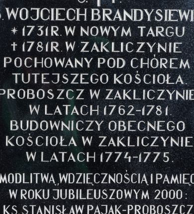 Zdjęcie nr 1: Tablica w kształcie stojącego prostokąta z kutą inskrypcją „Ś(więtej) P(amięci) / KS(IĄDZ) WOJCIECH BRANDYSIEWICZ / * 1731 R(OKU) W NOWYM TARGU /† 1781 R(OKU) W ZAKLICZYNIE / POCHOWANY POD CHÓREM / TUTEJSZEGO KOŚCIOŁA. / PROBOSZCZ W ZAKLICZYNIE / W LATACH 1762-1781. / BUDOWNICZY OBECNEGO / KOŚCIOŁA W ZAKLICZYNIE / W LATACH 1774-1775. / Z MODLITWĄ, WDZIĘCZNOŚCIĄ I PAMIĘCIĄ / W ROKU JUBILEUSZOWYM 2000: / KS(IĄDZ) STANISŁAW PAJĄK-PROBOSZCZ I WIERNI PARAFII ZAKLICZYN. / R(EQUIESCAT) I(N) P(ACE)”. U góry, pomiędzy literami „Ś” i „P” łaciński krzyżyk.