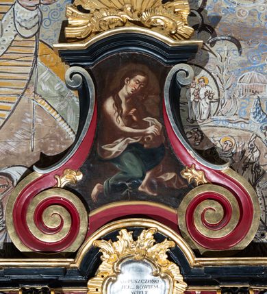 Zdjęcie nr 2: Konfesjonał o podstawie na planie półkola. Drzwi zamykające wejście do siedziska delikatnie wypukłe, ujęte pilastrami, dekorowanymi na trzonach prostokątnymi płycinami. Boczne, występujące ku górze ścianki ograniczające siedzisko zwieńczone wolutami. Ścianki zaplecka ujęte wolutami, które ozdobione są rocaille&#039;ami, na boku odgraniczone filarkami, zakończonymi profilowanym gzymsem, na którym ustawione wazony płomieniste z krzyżykami o trójlistnie zakończonych ramionach. Ścianka zaplecka zamknięta profilowanym gzymsem w kształcie nadwieszonego łuku, pośrodku rocaille&#039;owy kartusz z napisem w polu „ODPUSZCZONO / JEJ... BOWIEM / WIELE / UMIŁOWAŁA / ŁK 7, 47”. Zwieńczenie w kształcie wklęsło-wypukłym, po bokach ujęte dwiema esownicami, zamknięte łukiem nadwieszonym. W polu obraz św. Marii Magdaleny. U szczytu rokokowa muszla palmetowa. Z obu stron konfesjonału znajdują się dwa stopnie-klęczniki i podpórki na dłonie o esowato wyciętym przebiegu, a w ściankach flankujących z boków siedzisko księdza prześwity z kratą. Polichromia struktury w kolorze czerwonym, detale w kolorze czarnym, profilowania i ornamentyka złocone i srebrzone. 

Obraz św. Marii Magdaleny w kształcie wklęsło-wypukłym. W centrum kompozycji całopostaciowe przedstawienie świętej, zwróconej trzy czwarte w lewo w pozycji siedzącej, z głową przechyloną na lewe ramię, z prawą stopą cofniętą do tyłu. Święta Maria Magdalena w lewej dłoni trzyma krucyfiks, który przybliża do twarzy, a prawą wspiera na położonej na lewym kolanie czaszce. Twarz podłużna z wyraźnie zaznaczonym podbródkiem, małymi ustami, długim nosem i niemal zamkniętymi oczami i silnie zarumienionymi policzkami. Włosy długie, ciemnobrązowe, opadające lokami na ramiona i piersi. Święta jest półnaga, w pasie ubrana w zielony płaszcz o białej podszewce, który jest silnie drapowany. Po lewej stronie obrazu, u dołu widoczna jest roślinność. Tło bliżej nieokreślone, przypominające wejście do groty, a dookoła obrazu ciemnobrązowe.