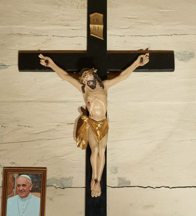 Zdjęcie nr 1: Rzeźba Chrystusa przybita do krzyża trzema gwoździami w głębokim zwisie na ramionach. Sylwetka szczupła o mocno podkreślonej, guzowatej linii żeber, z zaznaczonym mostkiem, kolana złączone, stopy założone w układzie prawa na lewą, ramiona delikatnie umięśnione, dwa palce u dłoni rozprostowane, głowa przechylona na prawe ramię. Twarz podłużna, okolona krótką brodą, usta delikatnie rozchylone, oczy przymknięte ze wzrokiem skierowanym w dół, nos długi i wąski. Włosy długie, ciemnobrązowe, opadają na plecy i dwoma puklami do przodu na ramiona, na głowie założona jest głęboko osadzona, złocona korona cierniowa. Perizonium złocone, zawiązane na guza na prawym boku i spływające łagodnymi falami wzdłuż prawego uda, z przodu układające się na kształt trójkątnej chusty. Z boku, dłoni, stóp i spod korony cierniowej spływają strużki krwi. Polichromia ciała naturalistyczna. Krzyż gładki, prosty, malowany na czarno; nad głową Chrystusa złocony titulus w formie pionowej banderoli z napisem „IN / RI”. Na krawędzi u nasady dolnej belki napis malowany białą farbą: „NS”. 
