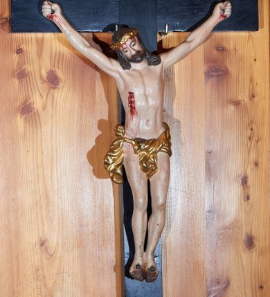 Zdjęcie nr 1: Rzeźba Chrystusa przybita do krzyża czterema gwoździami w głębokim zwisie na ramionach. Sylwetka szczupła o podkreślonej anatomii, głowa przechylona delikatnie na prawe ramię, dłonie silnie zaciśnięte, kolana rozdzielone, stopy złożone obok siebie, przebite oddzielnie. Twarz szczupła z szerokim, trójkątnym nosem, małymi oczami, okolona krótką brodą. Włosy długie, bujne i ciemnobrązowe, spływające na oba ramiona, rzeźbione w grube pasma; na głowie złocona korona cierniowa. Perizonium zawieszone na sznurze, z przodu z jednym końcem przewieszonym przez sznur, a z drugim zawiązanym na prawym boku, silnie drapowane. Z boku, dłoni, stóp i spod korony cierniowej spływają strużki krwi. Polichromia ciała naturalistyczna. Krzyż gładki, prosty i malowany na czarno; nad głową Chrystusa titulus w formie poziomej banderoli z napisem „I.N. / R.I.”. 
