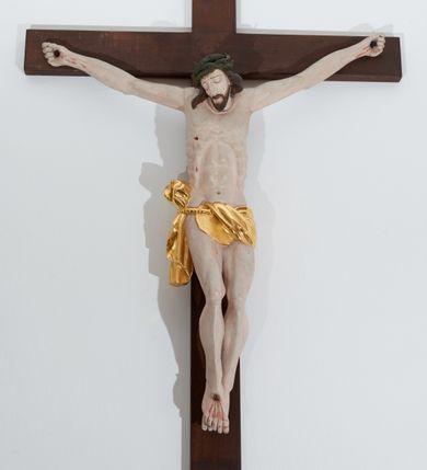 Zdjęcie nr 1: Chrystus przybity do krzyża trzema gwoździami. Sylwetka w delikatnym zwisie, o silnie zaznaczonej anatomii ciała, z guzowato podkreśloną linią żeber i delikatnie zaznaczonymi śladami męki; prawa stopa założona na lewą. Głowa delikatnie opadająca na prawe ramię, twarz podłużna i okolona krótkim zarostem, oczy zamknięte, nos podłużny i wąski, usta zamknięte; włosy długie, spływające na prawe ramię, a z lewej strony bujnie zawinięte do tyłu, na głowie szeroka, zielona korona cierniowa. Perizonium w formie tkaniny przewiązanej na sznurze na prawym boku, odsłaniające prawe udo. Krzyż drewniany, prosty. Nad głową Chrystusa zawieszony titulus w kształcie pionowej tabliczki z napisem „INRI”. Partie ciała polichromowane naturalistycznie, perizonium złocone.



