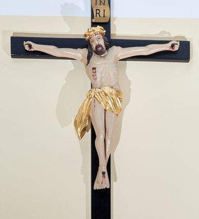 Zdjęcie nr 1: Rzeźba Chrystusa przybita do krzyża trzema gwoździami na silnie wyprostowanych ramionach. Sylwetka o mocno podkreślonej muskulaturze, kolana delikatnie ugięte, stopy w układzie prawa na lewą. Chrystus ma głowę przechyloną na prawe ramię. Twarz podłużna z szerokim i długim nosem, zamkniętymi oczami, na wpół otwartymi ustami, okolona krótką brodą. Włosy długie i ciemnobrązowe, spływające na prawe ramię, na głowie szeroka i złocona korona cierniowa. Perizonium złocone, ciasno oplatające biodra, przewiązane na prawym boku, z jednym końcem dłuższym i zwisającym wzdłuż prawego uda. Z boku, dłoni, stóp i spod korony cierniowej spływają strużki krwi. Polichromia ciała naturalistyczna. Krzyż gładki, prosty, pomalowany na czarno; nad głową Chrystusa titulus z napisem „IN / RI”. 