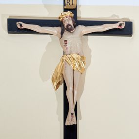 Zdjęcie nr 1: Rzeźba Chrystusa przybita do krzyża trzema gwoździami na silnie wyprostowanych ramionach. Sylwetka o mocno podkreślonej muskulaturze, kolana delikatnie ugięte, stopy w układzie prawa na lewą. Chrystus ma głowę przechyloną na prawe ramię. Twarz podłużna z szerokim i długim nosem, zamkniętymi oczami, na wpół otwartymi ustami, okolona krótką brodą. Włosy długie i ciemnobrązowe, spływające na prawe ramię, na głowie szeroka i złocona korona cierniowa. Perizonium złocone, ciasno oplatające biodra, przewiązane na prawym boku, z jednym końcem dłuższym i zwisającym wzdłuż prawego uda. Z boku, dłoni, stóp i spod korony cierniowej spływają strużki krwi. Polichromia ciała naturalistyczna. Krzyż gładki, prosty, pomalowany na czarno; nad głową Chrystusa titulus z napisem „IN / RI”. 