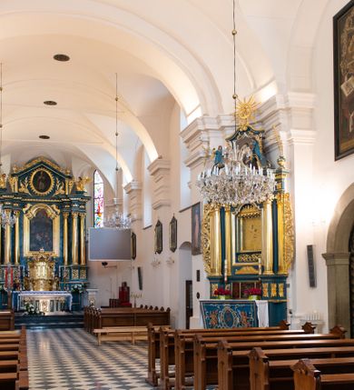 Zdjęcie nr 21: Kościół orientowany, jest budowlą murowaną z cegły i kamienia, na rzucie podłużnym. Korpus jednonawowy i trójprzęsłowy. Stosunkowo szerokie, trójprzęsłowe, zamknięte trójbocznie prezbiterium z przylegającą od północy zakrystią. Na osi kościoła przylega do fasady trójkondygnacyjna wieża z kruchtą w przyziemiu i przyległością od południa, w której mieszczą się prowadzące na wieżę schody.  Od południa i zachodu, na wysokości trzeciego przęsła do korpusu przylega kaplic na rzutach zbliżonych do kwadratów, z czego południową od wschodu i zachodu flankuje para krucht. Nawa, prezbiterium i kaplica północna przekryte są sklepieniami kolebkowymi z lunetami wspartymi na parach lub pojedynczych pilastrach. Kaplica południowa nakryta jest kopułą wspartą na 4 pendentywach. Artykulację ścian na zewnątrz korpusu nawowego i prezbiterium stanowi zespół przypór. Naroża kaplicy południowej ujmują zwielokrotnione pilastry wpierające obiegający bryłę gzyms wieńczący. Naroża kaplicy północnej ujmuje para neogotyckich przypór, natomiast północną ścianę wieńczy neogotycki szczyt schodkowy. 
Do wnętrza prowadzi 6 otworów drzwiowych – 1 w kruchcie w wieży ujęte kamienny, półkoliście zamkniętym portalem schodkowym z dwuskrzydłowymi drzwiami z nadświetlem, 1 zamknięte łukiem półkolistym w przyległości obok wieży, 3 w kruchtach flankujących kaplicę południową – z czego w zachodniej jedno w formie dużych dwuskrzydłowych drzwi z kwaterami bocznymi i nadświetlem, we wschodniej 2 ujęte prostokątnymi, kamiennymi portalami z wąskim nadświetlem i parą uszaków, zwieńczonych parą stykających się wolut z krzyżem na kuli w szczycie oraz 1 prowadzące do zakrystii. Okna korpusu nawowego i prezbiterium w kształcie stojących prostokątów zamkniętych półkoliście, z czego w prezbiterium są smukłe i wysokie. Okna kaplicy północnej zamknięte łukiem koszowym, natomiast kaplicy południowej w postaci prostokątów ujętych kamiennymi obramieniami z uszakami na narożach. 3 z 4 ścian wieży przeprute oknami, po 1 na każdej z kondygnacji, z czego na pierwszej zamknięte półkoliście, na drugiej w kształcie stojącego prostokąta i na trzeciej ostrołukowe. Wieżę wieńczy ceglany szczyt z wydzielonym gzymsami fryzem arkadkowym, wyżej 4 trójkątne szczyty umieszczone na osiach każdej ze ścian ujęte w narożach 4 małymi pinaklami i hełmem pośrodku w formie wysokiego pinakla. Korpus nawowy i prezbiterium przekrywa dach dwuspadowy, kryty blachą, z pinaklową wieżyczką na sygnaturkę na połączeniu tych przestrzeni, kaplicę południową kopuła z latarnią, przylegające do niej kruchty dachy pulpitowe, natomiast kaplica północna ma dach dwuspadowy. Otynkowane ściany kościoła są pomalowane w kolorze białym, miejscami pozostawiony kamienny mur.     
