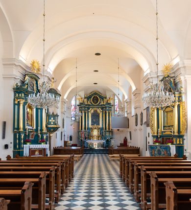 Zdjęcie nr 19: Kościół orientowany, jest budowlą murowaną z cegły i kamienia, na rzucie podłużnym. Korpus jednonawowy i trójprzęsłowy. Stosunkowo szerokie, trójprzęsłowe, zamknięte trójbocznie prezbiterium z przylegającą od północy zakrystią. Na osi kościoła przylega do fasady trójkondygnacyjna wieża z kruchtą w przyziemiu i przyległością od południa, w której mieszczą się prowadzące na wieżę schody.  Od południa i zachodu, na wysokości trzeciego przęsła do korpusu przylega kaplic na rzutach zbliżonych do kwadratów, z czego południową od wschodu i zachodu flankuje para krucht. Nawa, prezbiterium i kaplica północna przekryte są sklepieniami kolebkowymi z lunetami wspartymi na parach lub pojedynczych pilastrach. Kaplica południowa nakryta jest kopułą wspartą na 4 pendentywach. Artykulację ścian na zewnątrz korpusu nawowego i prezbiterium stanowi zespół przypór. Naroża kaplicy południowej ujmują zwielokrotnione pilastry wpierające obiegający bryłę gzyms wieńczący. Naroża kaplicy północnej ujmuje para neogotyckich przypór, natomiast północną ścianę wieńczy neogotycki szczyt schodkowy. 
Do wnętrza prowadzi 6 otworów drzwiowych – 1 w kruchcie w wieży ujęte kamienny, półkoliście zamkniętym portalem schodkowym z dwuskrzydłowymi drzwiami z nadświetlem, 1 zamknięte łukiem półkolistym w przyległości obok wieży, 3 w kruchtach flankujących kaplicę południową – z czego w zachodniej jedno w formie dużych dwuskrzydłowych drzwi z kwaterami bocznymi i nadświetlem, we wschodniej 2 ujęte prostokątnymi, kamiennymi portalami z wąskim nadświetlem i parą uszaków, zwieńczonych parą stykających się wolut z krzyżem na kuli w szczycie oraz 1 prowadzące do zakrystii. Okna korpusu nawowego i prezbiterium w kształcie stojących prostokątów zamkniętych półkoliście, z czego w prezbiterium są smukłe i wysokie. Okna kaplicy północnej zamknięte łukiem koszowym, natomiast kaplicy południowej w postaci prostokątów ujętych kamiennymi obramieniami z uszakami na narożach. 3 z 4 ścian wieży przeprute oknami, po 1 na każdej z kondygnacji, z czego na pierwszej zamknięte półkoliście, na drugiej w kształcie stojącego prostokąta i na trzeciej ostrołukowe. Wieżę wieńczy ceglany szczyt z wydzielonym gzymsami fryzem arkadkowym, wyżej 4 trójkątne szczyty umieszczone na osiach każdej ze ścian ujęte w narożach 4 małymi pinaklami i hełmem pośrodku w formie wysokiego pinakla. Korpus nawowy i prezbiterium przekrywa dach dwuspadowy, kryty blachą, z pinaklową wieżyczką na sygnaturkę na połączeniu tych przestrzeni, kaplicę południową kopuła z latarnią, przylegające do niej kruchty dachy pulpitowe, natomiast kaplica północna ma dach dwuspadowy. Otynkowane ściany kościoła są pomalowane w kolorze białym, miejscami pozostawiony kamienny mur.     
