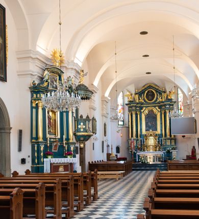 Zdjęcie nr 20: Kościół orientowany, jest budowlą murowaną z cegły i kamienia, na rzucie podłużnym. Korpus jednonawowy i trójprzęsłowy. Stosunkowo szerokie, trójprzęsłowe, zamknięte trójbocznie prezbiterium z przylegającą od północy zakrystią. Na osi kościoła przylega do fasady trójkondygnacyjna wieża z kruchtą w przyziemiu i przyległością od południa, w której mieszczą się prowadzące na wieżę schody.  Od południa i zachodu, na wysokości trzeciego przęsła do korpusu przylega kaplic na rzutach zbliżonych do kwadratów, z czego południową od wschodu i zachodu flankuje para krucht. Nawa, prezbiterium i kaplica północna przekryte są sklepieniami kolebkowymi z lunetami wspartymi na parach lub pojedynczych pilastrach. Kaplica południowa nakryta jest kopułą wspartą na 4 pendentywach. Artykulację ścian na zewnątrz korpusu nawowego i prezbiterium stanowi zespół przypór. Naroża kaplicy południowej ujmują zwielokrotnione pilastry wpierające obiegający bryłę gzyms wieńczący. Naroża kaplicy północnej ujmuje para neogotyckich przypór, natomiast północną ścianę wieńczy neogotycki szczyt schodkowy. 
Do wnętrza prowadzi 6 otworów drzwiowych – 1 w kruchcie w wieży ujęte kamienny, półkoliście zamkniętym portalem schodkowym z dwuskrzydłowymi drzwiami z nadświetlem, 1 zamknięte łukiem półkolistym w przyległości obok wieży, 3 w kruchtach flankujących kaplicę południową – z czego w zachodniej jedno w formie dużych dwuskrzydłowych drzwi z kwaterami bocznymi i nadświetlem, we wschodniej 2 ujęte prostokątnymi, kamiennymi portalami z wąskim nadświetlem i parą uszaków, zwieńczonych parą stykających się wolut z krzyżem na kuli w szczycie oraz 1 prowadzące do zakrystii. Okna korpusu nawowego i prezbiterium w kształcie stojących prostokątów zamkniętych półkoliście, z czego w prezbiterium są smukłe i wysokie. Okna kaplicy północnej zamknięte łukiem koszowym, natomiast kaplicy południowej w postaci prostokątów ujętych kamiennymi obramieniami z uszakami na narożach. 3 z 4 ścian wieży przeprute oknami, po 1 na każdej z kondygnacji, z czego na pierwszej zamknięte półkoliście, na drugiej w kształcie stojącego prostokąta i na trzeciej ostrołukowe. Wieżę wieńczy ceglany szczyt z wydzielonym gzymsami fryzem arkadkowym, wyżej 4 trójkątne szczyty umieszczone na osiach każdej ze ścian ujęte w narożach 4 małymi pinaklami i hełmem pośrodku w formie wysokiego pinakla. Korpus nawowy i prezbiterium przekrywa dach dwuspadowy, kryty blachą, z pinaklową wieżyczką na sygnaturkę na połączeniu tych przestrzeni, kaplicę południową kopuła z latarnią, przylegające do niej kruchty dachy pulpitowe, natomiast kaplica północna ma dach dwuspadowy. Otynkowane ściany kościoła są pomalowane w kolorze białym, miejscami pozostawiony kamienny mur.     
