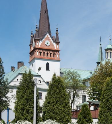 Zdjęcie nr 1: Kościół orientowany, jest budowlą murowaną z cegły i kamienia, na rzucie podłużnym. Korpus jednonawowy i trójprzęsłowy. Stosunkowo szerokie, trójprzęsłowe, zamknięte trójbocznie prezbiterium z przylegającą od północy zakrystią. Na osi kościoła przylega do fasady trójkondygnacyjna wieża z kruchtą w przyziemiu i przyległością od południa, w której mieszczą się prowadzące na wieżę schody.  Od południa i zachodu, na wysokości trzeciego przęsła do korpusu przylega kaplic na rzutach zbliżonych do kwadratów, z czego południową od wschodu i zachodu flankuje para krucht. Nawa, prezbiterium i kaplica północna przekryte są sklepieniami kolebkowymi z lunetami wspartymi na parach lub pojedynczych pilastrach. Kaplica południowa nakryta jest kopułą wspartą na 4 pendentywach. Artykulację ścian na zewnątrz korpusu nawowego i prezbiterium stanowi zespół przypór. Naroża kaplicy południowej ujmują zwielokrotnione pilastry wpierające obiegający bryłę gzyms wieńczący. Naroża kaplicy północnej ujmuje para neogotyckich przypór, natomiast północną ścianę wieńczy neogotycki szczyt schodkowy. 
Do wnętrza prowadzi 6 otworów drzwiowych – 1 w kruchcie w wieży ujęte kamienny, półkoliście zamkniętym portalem schodkowym z dwuskrzydłowymi drzwiami z nadświetlem, 1 zamknięte łukiem półkolistym w przyległości obok wieży, 3 w kruchtach flankujących kaplicę południową – z czego w zachodniej jedno w formie dużych dwuskrzydłowych drzwi z kwaterami bocznymi i nadświetlem, we wschodniej 2 ujęte prostokątnymi, kamiennymi portalami z wąskim nadświetlem i parą uszaków, zwieńczonych parą stykających się wolut z krzyżem na kuli w szczycie oraz 1 prowadzące do zakrystii. Okna korpusu nawowego i prezbiterium w kształcie stojących prostokątów zamkniętych półkoliście, z czego w prezbiterium są smukłe i wysokie. Okna kaplicy północnej zamknięte łukiem koszowym, natomiast kaplicy południowej w postaci prostokątów ujętych kamiennymi obramieniami z uszakami na narożach. 3 z 4 ścian wieży przeprute oknami, po 1 na każdej z kondygnacji, z czego na pierwszej zamknięte półkoliście, na drugiej w kształcie stojącego prostokąta i na trzeciej ostrołukowe. Wieżę wieńczy ceglany szczyt z wydzielonym gzymsami fryzem arkadkowym, wyżej 4 trójkątne szczyty umieszczone na osiach każdej ze ścian ujęte w narożach 4 małymi pinaklami i hełmem pośrodku w formie wysokiego pinakla. Korpus nawowy i prezbiterium przekrywa dach dwuspadowy, kryty blachą, z pinaklową wieżyczką na sygnaturkę na połączeniu tych przestrzeni, kaplicę południową kopuła z latarnią, przylegające do niej kruchty dachy pulpitowe, natomiast kaplica północna ma dach dwuspadowy. Otynkowane ściany kościoła są pomalowane w kolorze białym, miejscami pozostawiony kamienny mur.     
