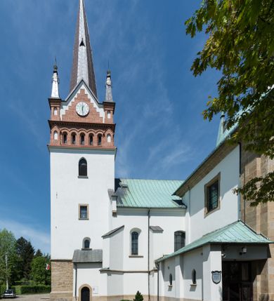 Zdjęcie nr 2: Kościół orientowany, jest budowlą murowaną z cegły i kamienia, na rzucie podłużnym. Korpus jednonawowy i trójprzęsłowy. Stosunkowo szerokie, trójprzęsłowe, zamknięte trójbocznie prezbiterium z przylegającą od północy zakrystią. Na osi kościoła przylega do fasady trójkondygnacyjna wieża z kruchtą w przyziemiu i przyległością od południa, w której mieszczą się prowadzące na wieżę schody.  Od południa i zachodu, na wysokości trzeciego przęsła do korpusu przylega kaplic na rzutach zbliżonych do kwadratów, z czego południową od wschodu i zachodu flankuje para krucht. Nawa, prezbiterium i kaplica północna przekryte są sklepieniami kolebkowymi z lunetami wspartymi na parach lub pojedynczych pilastrach. Kaplica południowa nakryta jest kopułą wspartą na 4 pendentywach. Artykulację ścian na zewnątrz korpusu nawowego i prezbiterium stanowi zespół przypór. Naroża kaplicy południowej ujmują zwielokrotnione pilastry wpierające obiegający bryłę gzyms wieńczący. Naroża kaplicy północnej ujmuje para neogotyckich przypór, natomiast północną ścianę wieńczy neogotycki szczyt schodkowy. 
Do wnętrza prowadzi 6 otworów drzwiowych – 1 w kruchcie w wieży ujęte kamienny, półkoliście zamkniętym portalem schodkowym z dwuskrzydłowymi drzwiami z nadświetlem, 1 zamknięte łukiem półkolistym w przyległości obok wieży, 3 w kruchtach flankujących kaplicę południową – z czego w zachodniej jedno w formie dużych dwuskrzydłowych drzwi z kwaterami bocznymi i nadświetlem, we wschodniej 2 ujęte prostokątnymi, kamiennymi portalami z wąskim nadświetlem i parą uszaków, zwieńczonych parą stykających się wolut z krzyżem na kuli w szczycie oraz 1 prowadzące do zakrystii. Okna korpusu nawowego i prezbiterium w kształcie stojących prostokątów zamkniętych półkoliście, z czego w prezbiterium są smukłe i wysokie. Okna kaplicy północnej zamknięte łukiem koszowym, natomiast kaplicy południowej w postaci prostokątów ujętych kamiennymi obramieniami z uszakami na narożach. 3 z 4 ścian wieży przeprute oknami, po 1 na każdej z kondygnacji, z czego na pierwszej zamknięte półkoliście, na drugiej w kształcie stojącego prostokąta i na trzeciej ostrołukowe. Wieżę wieńczy ceglany szczyt z wydzielonym gzymsami fryzem arkadkowym, wyżej 4 trójkątne szczyty umieszczone na osiach każdej ze ścian ujęte w narożach 4 małymi pinaklami i hełmem pośrodku w formie wysokiego pinakla. Korpus nawowy i prezbiterium przekrywa dach dwuspadowy, kryty blachą, z pinaklową wieżyczką na sygnaturkę na połączeniu tych przestrzeni, kaplicę południową kopuła z latarnią, przylegające do niej kruchty dachy pulpitowe, natomiast kaplica północna ma dach dwuspadowy. Otynkowane ściany kościoła są pomalowane w kolorze białym, miejscami pozostawiony kamienny mur.     
