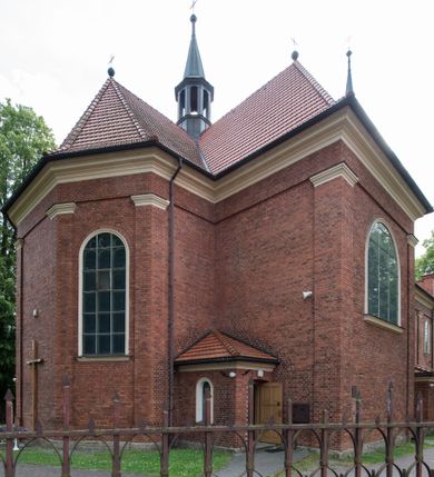 Zdjęcie nr 9: Kościół jest położony w centrum wsi, na południe od głównej drogi, na placu otoczonym płotem na kamiennej podmurówce. Wejście na plac kościelny prowadzi przez główną bramę od zachodu oraz drugą od północnego-wschodu. Kościół jest budowlą założoną na planie krzyża łacińskiego, murowaną, orientowaną z delikatnym odchyleniem ku południowi, jednonawową z transeptem, z prezbiterium zamkniętym trójbocznie, przy którym od północy jest zakrystia z emporą, a od południa kaplica. Wnętrze nawy głównej artykułowe jest dwiema płytkimi wnękami, zakończonymi półkoliście, w których w górnej części umieszczone są trójdzielne okna z maswerkami i witrażami. W prezbiterium i kaplicy sklepienie krzyżowo-żebrowe, w nawie gwieździste bez żeber. Nawę od prezbiterium oraz ramion transeptu oddzielają półkoliście zamknięte arkady. Na ścianie arkady tęczowej napis: „CHWAŁA CI TRÓJCO ŚWIĘTA”. W ramionach transeptu pojedyncze okna prostokątne, zamknięte półkoliście. Kolejne dwa okna, lecz węższe znajdują się w prezbiterium. 

Fasada dwukondygnacyjna z dostawioną wieżą na planie kwadratu. W dolnej kondygnacji fasada artykułowana parą pilastrów w narożach, podtrzymujących profilowany gzyms. Pośrodku główne wejście do kościoła zaakcentowane schodami i monumentalnym portalem z wimpergą i masywnymi kamiennymi węgarami. W górnej kondygnacji fasady uwidoczniona sylwetka wieży z każdej strony flankowana w narożach parą lizen podtrzymujących niepełne belkowanie i trójkątne przyczółki. Od frontu, po bokach wieży spływy wolutowe, w polu półkoliście zamknięte okno, a nad nim okrągłe. Na ścianach bocznych wieży analogiczne oculusy. Na szczycie wieży wysoka iglica. Pozostałe ściany kościoła artykułowe pilastrami, podtrzymującymi niepełne belkowanie zamknięte gzymsem podokapowym. Dach dwuspadowy, nakryty dachówką.

