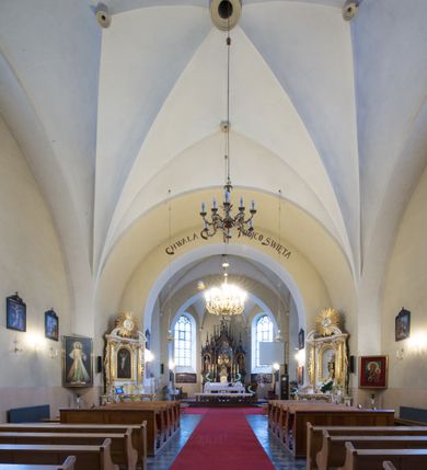 Zdjęcie nr 13: Kościół jest położony w centrum wsi, na południe od głównej drogi, na placu otoczonym płotem na kamiennej podmurówce. Wejście na plac kościelny prowadzi przez główną bramę od zachodu oraz drugą od północnego-wschodu. Kościół jest budowlą założoną na planie krzyża łacińskiego, murowaną, orientowaną z delikatnym odchyleniem ku południowi, jednonawową z transeptem, z prezbiterium zamkniętym trójbocznie, przy którym od północy jest zakrystia z emporą, a od południa kaplica. Wnętrze nawy głównej artykułowe jest dwiema płytkimi wnękami, zakończonymi półkoliście, w których w górnej części umieszczone są trójdzielne okna z maswerkami i witrażami. W prezbiterium i kaplicy sklepienie krzyżowo-żebrowe, w nawie gwieździste bez żeber. Nawę od prezbiterium oraz ramion transeptu oddzielają półkoliście zamknięte arkady. Na ścianie arkady tęczowej napis: „CHWAŁA CI TRÓJCO ŚWIĘTA”. W ramionach transeptu pojedyncze okna prostokątne, zamknięte półkoliście. Kolejne dwa okna, lecz węższe znajdują się w prezbiterium. 

Fasada dwukondygnacyjna z dostawioną wieżą na planie kwadratu. W dolnej kondygnacji fasada artykułowana parą pilastrów w narożach, podtrzymujących profilowany gzyms. Pośrodku główne wejście do kościoła zaakcentowane schodami i monumentalnym portalem z wimpergą i masywnymi kamiennymi węgarami. W górnej kondygnacji fasady uwidoczniona sylwetka wieży z każdej strony flankowana w narożach parą lizen podtrzymujących niepełne belkowanie i trójkątne przyczółki. Od frontu, po bokach wieży spływy wolutowe, w polu półkoliście zamknięte okno, a nad nim okrągłe. Na ścianach bocznych wieży analogiczne oculusy. Na szczycie wieży wysoka iglica. Pozostałe ściany kościoła artykułowe pilastrami, podtrzymującymi niepełne belkowanie zamknięte gzymsem podokapowym. Dach dwuspadowy, nakryty dachówką.

