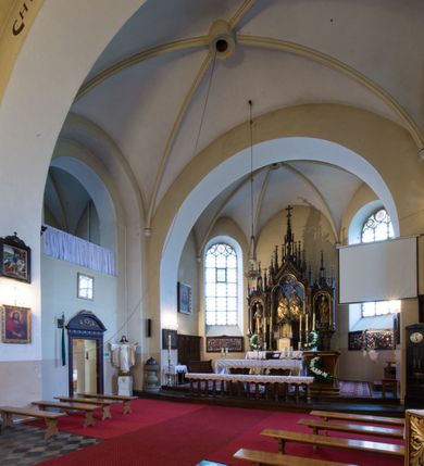 Zdjęcie nr 4: Kościół jest położony w centrum wsi, na południe od głównej drogi, na placu otoczonym płotem na kamiennej podmurówce. Wejście na plac kościelny prowadzi przez główną bramę od zachodu oraz drugą od północnego-wschodu. Kościół jest budowlą założoną na planie krzyża łacińskiego, murowaną, orientowaną z delikatnym odchyleniem ku południowi, jednonawową z transeptem, z prezbiterium zamkniętym trójbocznie, przy którym od północy jest zakrystia z emporą, a od południa kaplica. Wnętrze nawy głównej artykułowe jest dwiema płytkimi wnękami, zakończonymi półkoliście, w których w górnej części umieszczone są trójdzielne okna z maswerkami i witrażami. W prezbiterium i kaplicy sklepienie krzyżowo-żebrowe, w nawie gwieździste bez żeber. Nawę od prezbiterium oraz ramion transeptu oddzielają półkoliście zamknięte arkady. Na ścianie arkady tęczowej napis: „CHWAŁA CI TRÓJCO ŚWIĘTA”. W ramionach transeptu pojedyncze okna prostokątne, zamknięte półkoliście. Kolejne dwa okna, lecz węższe znajdują się w prezbiterium. 

Fasada dwukondygnacyjna z dostawioną wieżą na planie kwadratu. W dolnej kondygnacji fasada artykułowana parą pilastrów w narożach, podtrzymujących profilowany gzyms. Pośrodku główne wejście do kościoła zaakcentowane schodami i monumentalnym portalem z wimpergą i masywnymi kamiennymi węgarami. W górnej kondygnacji fasady uwidoczniona sylwetka wieży z każdej strony flankowana w narożach parą lizen podtrzymujących niepełne belkowanie i trójkątne przyczółki. Od frontu, po bokach wieży spływy wolutowe, w polu półkoliście zamknięte okno, a nad nim okrągłe. Na ścianach bocznych wieży analogiczne oculusy. Na szczycie wieży wysoka iglica. Pozostałe ściany kościoła artykułowe pilastrami, podtrzymującymi niepełne belkowanie zamknięte gzymsem podokapowym. Dach dwuspadowy, nakryty dachówką.

