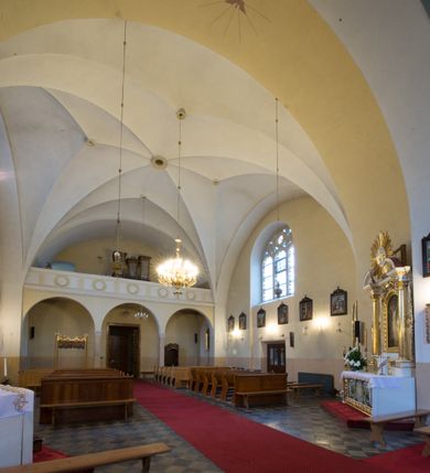 Zdjęcie nr 7: Kościół jest położony w centrum wsi, na południe od głównej drogi, na placu otoczonym płotem na kamiennej podmurówce. Wejście na plac kościelny prowadzi przez główną bramę od zachodu oraz drugą od północnego-wschodu. Kościół jest budowlą założoną na planie krzyża łacińskiego, murowaną, orientowaną z delikatnym odchyleniem ku południowi, jednonawową z transeptem, z prezbiterium zamkniętym trójbocznie, przy którym od północy jest zakrystia z emporą, a od południa kaplica. Wnętrze nawy głównej artykułowe jest dwiema płytkimi wnękami, zakończonymi półkoliście, w których w górnej części umieszczone są trójdzielne okna z maswerkami i witrażami. W prezbiterium i kaplicy sklepienie krzyżowo-żebrowe, w nawie gwieździste bez żeber. Nawę od prezbiterium oraz ramion transeptu oddzielają półkoliście zamknięte arkady. Na ścianie arkady tęczowej napis: „CHWAŁA CI TRÓJCO ŚWIĘTA”. W ramionach transeptu pojedyncze okna prostokątne, zamknięte półkoliście. Kolejne dwa okna, lecz węższe znajdują się w prezbiterium. 

Fasada dwukondygnacyjna z dostawioną wieżą na planie kwadratu. W dolnej kondygnacji fasada artykułowana parą pilastrów w narożach, podtrzymujących profilowany gzyms. Pośrodku główne wejście do kościoła zaakcentowane schodami i monumentalnym portalem z wimpergą i masywnymi kamiennymi węgarami. W górnej kondygnacji fasady uwidoczniona sylwetka wieży z każdej strony flankowana w narożach parą lizen podtrzymujących niepełne belkowanie i trójkątne przyczółki. Od frontu, po bokach wieży spływy wolutowe, w polu półkoliście zamknięte okno, a nad nim okrągłe. Na ścianach bocznych wieży analogiczne oculusy. Na szczycie wieży wysoka iglica. Pozostałe ściany kościoła artykułowe pilastrami, podtrzymującymi niepełne belkowanie zamknięte gzymsem podokapowym. Dach dwuspadowy, nakryty dachówką.

