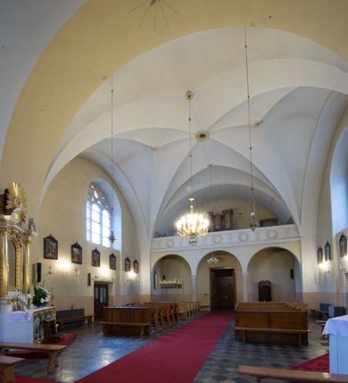 Zdjęcie nr 8: Kościół jest położony w centrum wsi, na południe od głównej drogi, na placu otoczonym płotem na kamiennej podmurówce. Wejście na plac kościelny prowadzi przez główną bramę od zachodu oraz drugą od północnego-wschodu. Kościół jest budowlą założoną na planie krzyża łacińskiego, murowaną, orientowaną z delikatnym odchyleniem ku południowi, jednonawową z transeptem, z prezbiterium zamkniętym trójbocznie, przy którym od północy jest zakrystia z emporą, a od południa kaplica. Wnętrze nawy głównej artykułowe jest dwiema płytkimi wnękami, zakończonymi półkoliście, w których w górnej części umieszczone są trójdzielne okna z maswerkami i witrażami. W prezbiterium i kaplicy sklepienie krzyżowo-żebrowe, w nawie gwieździste bez żeber. Nawę od prezbiterium oraz ramion transeptu oddzielają półkoliście zamknięte arkady. Na ścianie arkady tęczowej napis: „CHWAŁA CI TRÓJCO ŚWIĘTA”. W ramionach transeptu pojedyncze okna prostokątne, zamknięte półkoliście. Kolejne dwa okna, lecz węższe znajdują się w prezbiterium. 

Fasada dwukondygnacyjna z dostawioną wieżą na planie kwadratu. W dolnej kondygnacji fasada artykułowana parą pilastrów w narożach, podtrzymujących profilowany gzyms. Pośrodku główne wejście do kościoła zaakcentowane schodami i monumentalnym portalem z wimpergą i masywnymi kamiennymi węgarami. W górnej kondygnacji fasady uwidoczniona sylwetka wieży z każdej strony flankowana w narożach parą lizen podtrzymujących niepełne belkowanie i trójkątne przyczółki. Od frontu, po bokach wieży spływy wolutowe, w polu półkoliście zamknięte okno, a nad nim okrągłe. Na ścianach bocznych wieży analogiczne oculusy. Na szczycie wieży wysoka iglica. Pozostałe ściany kościoła artykułowe pilastrami, podtrzymującymi niepełne belkowanie zamknięte gzymsem podokapowym. Dach dwuspadowy, nakryty dachówką.

