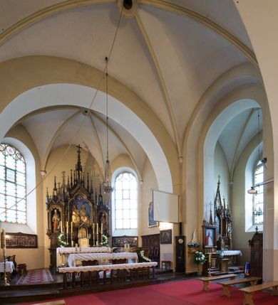 Zdjęcie nr 3: Kościół jest położony w centrum wsi, na południe od głównej drogi, na placu otoczonym płotem na kamiennej podmurówce. Wejście na plac kościelny prowadzi przez główną bramę od zachodu oraz drugą od północnego-wschodu. Kościół jest budowlą założoną na planie krzyża łacińskiego, murowaną, orientowaną z delikatnym odchyleniem ku południowi, jednonawową z transeptem, z prezbiterium zamkniętym trójbocznie, przy którym od północy jest zakrystia z emporą, a od południa kaplica. Wnętrze nawy głównej artykułowe jest dwiema płytkimi wnękami, zakończonymi półkoliście, w których w górnej części umieszczone są trójdzielne okna z maswerkami i witrażami. W prezbiterium i kaplicy sklepienie krzyżowo-żebrowe, w nawie gwieździste bez żeber. Nawę od prezbiterium oraz ramion transeptu oddzielają półkoliście zamknięte arkady. Na ścianie arkady tęczowej napis: „CHWAŁA CI TRÓJCO ŚWIĘTA”. W ramionach transeptu pojedyncze okna prostokątne, zamknięte półkoliście. Kolejne dwa okna, lecz węższe znajdują się w prezbiterium. 

Fasada dwukondygnacyjna z dostawioną wieżą na planie kwadratu. W dolnej kondygnacji fasada artykułowana parą pilastrów w narożach, podtrzymujących profilowany gzyms. Pośrodku główne wejście do kościoła zaakcentowane schodami i monumentalnym portalem z wimpergą i masywnymi kamiennymi węgarami. W górnej kondygnacji fasady uwidoczniona sylwetka wieży z każdej strony flankowana w narożach parą lizen podtrzymujących niepełne belkowanie i trójkątne przyczółki. Od frontu, po bokach wieży spływy wolutowe, w polu półkoliście zamknięte okno, a nad nim okrągłe. Na ścianach bocznych wieży analogiczne oculusy. Na szczycie wieży wysoka iglica. Pozostałe ściany kościoła artykułowe pilastrami, podtrzymującymi niepełne belkowanie zamknięte gzymsem podokapowym. Dach dwuspadowy, nakryty dachówką.

