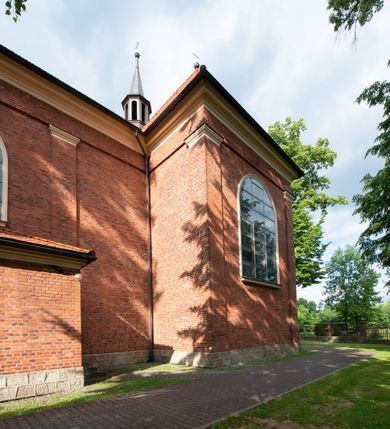 Zdjęcie nr 12: Kościół jest położony w centrum wsi, na południe od głównej drogi, na placu otoczonym płotem na kamiennej podmurówce. Wejście na plac kościelny prowadzi przez główną bramę od zachodu oraz drugą od północnego-wschodu. Kościół jest budowlą założoną na planie krzyża łacińskiego, murowaną, orientowaną z delikatnym odchyleniem ku południowi, jednonawową z transeptem, z prezbiterium zamkniętym trójbocznie, przy którym od północy jest zakrystia z emporą, a od południa kaplica. Wnętrze nawy głównej artykułowe jest dwiema płytkimi wnękami, zakończonymi półkoliście, w których w górnej części umieszczone są trójdzielne okna z maswerkami i witrażami. W prezbiterium i kaplicy sklepienie krzyżowo-żebrowe, w nawie gwieździste bez żeber. Nawę od prezbiterium oraz ramion transeptu oddzielają półkoliście zamknięte arkady. Na ścianie arkady tęczowej napis: „CHWAŁA CI TRÓJCO ŚWIĘTA”. W ramionach transeptu pojedyncze okna prostokątne, zamknięte półkoliście. Kolejne dwa okna, lecz węższe znajdują się w prezbiterium. 

Fasada dwukondygnacyjna z dostawioną wieżą na planie kwadratu. W dolnej kondygnacji fasada artykułowana parą pilastrów w narożach, podtrzymujących profilowany gzyms. Pośrodku główne wejście do kościoła zaakcentowane schodami i monumentalnym portalem z wimpergą i masywnymi kamiennymi węgarami. W górnej kondygnacji fasady uwidoczniona sylwetka wieży z każdej strony flankowana w narożach parą lizen podtrzymujących niepełne belkowanie i trójkątne przyczółki. Od frontu, po bokach wieży spływy wolutowe, w polu półkoliście zamknięte okno, a nad nim okrągłe. Na ścianach bocznych wieży analogiczne oculusy. Na szczycie wieży wysoka iglica. Pozostałe ściany kościoła artykułowe pilastrami, podtrzymującymi niepełne belkowanie zamknięte gzymsem podokapowym. Dach dwuspadowy, nakryty dachówką.

