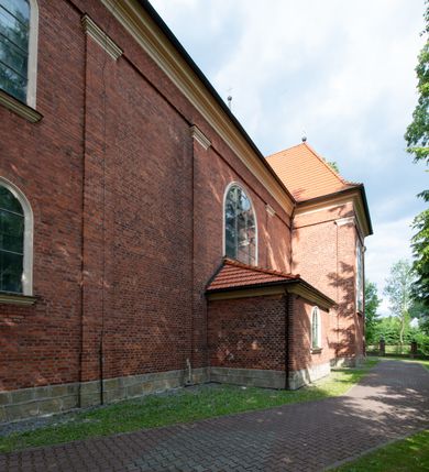 Zdjęcie nr 11: Kościół jest położony w centrum wsi, na południe od głównej drogi, na placu otoczonym płotem na kamiennej podmurówce. Wejście na plac kościelny prowadzi przez główną bramę od zachodu oraz drugą od północnego-wschodu. Kościół jest budowlą założoną na planie krzyża łacińskiego, murowaną, orientowaną z delikatnym odchyleniem ku południowi, jednonawową z transeptem, z prezbiterium zamkniętym trójbocznie, przy którym od północy jest zakrystia z emporą, a od południa kaplica. Wnętrze nawy głównej artykułowe jest dwiema płytkimi wnękami, zakończonymi półkoliście, w których w górnej części umieszczone są trójdzielne okna z maswerkami i witrażami. W prezbiterium i kaplicy sklepienie krzyżowo-żebrowe, w nawie gwieździste bez żeber. Nawę od prezbiterium oraz ramion transeptu oddzielają półkoliście zamknięte arkady. Na ścianie arkady tęczowej napis: „CHWAŁA CI TRÓJCO ŚWIĘTA”. W ramionach transeptu pojedyncze okna prostokątne, zamknięte półkoliście. Kolejne dwa okna, lecz węższe znajdują się w prezbiterium. 

Fasada dwukondygnacyjna z dostawioną wieżą na planie kwadratu. W dolnej kondygnacji fasada artykułowana parą pilastrów w narożach, podtrzymujących profilowany gzyms. Pośrodku główne wejście do kościoła zaakcentowane schodami i monumentalnym portalem z wimpergą i masywnymi kamiennymi węgarami. W górnej kondygnacji fasady uwidoczniona sylwetka wieży z każdej strony flankowana w narożach parą lizen podtrzymujących niepełne belkowanie i trójkątne przyczółki. Od frontu, po bokach wieży spływy wolutowe, w polu półkoliście zamknięte okno, a nad nim okrągłe. Na ścianach bocznych wieży analogiczne oculusy. Na szczycie wieży wysoka iglica. Pozostałe ściany kościoła artykułowe pilastrami, podtrzymującymi niepełne belkowanie zamknięte gzymsem podokapowym. Dach dwuspadowy, nakryty dachówką.

