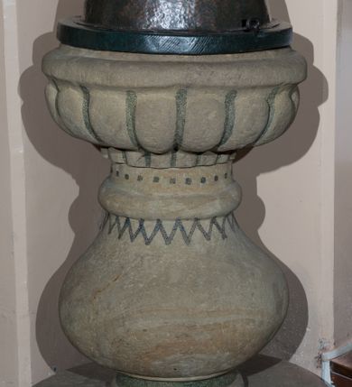 Zdjęcie nr 1: Kamienna chrzcielnica na kolistej stopie. Trzon w dolnej partii w formie półwałka przechodzący w gruszkowy nodus zwieńczony półwałkiem. Czara w kształcie spłaszczonej półkuli, z półkoliście formowanym wylewem, zdobiona motywem puklowania. Nodus w górnej partii zdobiony malowanym, czarnym zygzakiem, górna partia trzonu z motywem czarnych kropek. Pokrywa blaszana w kształcie półkulistym z okrągłym, drewnianym kołnierzem, zwieńczona kulą z krzyżem równoramiennym. Wewnątrz kociołek z miedzianej, kutej blachy, z blaszaną pokrywą.