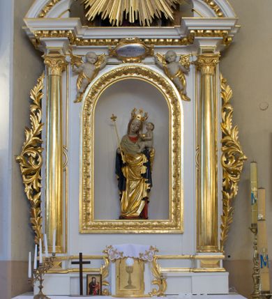 Zdjęcie nr 1: Ołtarz drewniany, prostopadłościenny, na jednostopniowej podstawie. Mensa drewniana z portatylem z marmuru dębnickiego z kwadratowym reservaculum na relikwie św. Konstancji i św. Teodora. Antepedium w formie leżącego  prostokąta ujętego grubą ramą, dekorowaną płaskorzeźbionym akantem. W polu, w centrum malowany na desce rollwerk z monogramem Marii w polu, ujęty wolutami utworzonymi z ornamentu roślinnego o wici zakończonej kampanulą. Tabernakulum w formie prostopadłościennej skrzynki o delikatnie wypukłej ściance frontowej. Całość zamknięta opasującym je z trzech stron gzymsem przyjmującym nad polem środkowym kształt łuku segmentowego podtrzymywanego przez dwie konsole utworzone z akantu. Drzwiczki w kształcie stojącego prostokąta zamkniętego łukiem półkolistym nadwieszonym, ujęte ramą. W polu ryte przedstawienie kielicha z hostią. Tabernakulum flankowane spływami wolutowymi utworzonymi z akantu. Nastawa ołtarzowa architektoniczna, jednoosiowa, jednokondygnacyjna ze zwieńczeniem, na niewielkim cokole. Kondygnacja ujęta parą kolumn o kapitelach kompozytowych dźwigających pełne belkowanie wyłamane na ich osi oraz przerwany półkolisty przyczółek. W polu środkowym nisza w formie stojącego prostokąta zamkniętego łukiem półkolistym, ujęta ramą z figurą Matki Boskiej z Dzieciątkiem. Zwieńczenie w formie medalionu z płaskorzeźbionym monogramem Marii w glorii promienistej. W przyłuczach niszy w polu środkowym para puttów podtrzymujących owalny kartusz z napisem w polu „WIELBIJ / DUSZO MOJA PANA / ŚW(IĘTY) ŁUKASZ I R(OZDZIAŁ)”. Kondygnacja flankowana uszami utworzonymi z suchego akantu. Gzyms oraz przerwany przyczółek dekorowane kimationem. Struktura polichromowana w kolorze białym, ornamentyka, profile i kolumny złocone.
