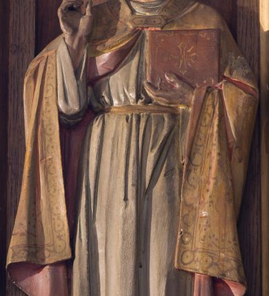 Zdjęcie nr 9: Nastawa ołtarzowa architektoniczna, jednokondygnacyjna, trójosiowa. Ołtarz kamienny, prostopadłościenny, ustawiony na dwustopniowej podstawie. Mensa kamienna, silnie wysunięta, podtrzymywana przez dwie kamienne kolumienki. Antepedium podzielone na trzy kwadratowe pola z płycinami, w środkowej wysuniętej do przodu medalion z monogramem IHS w polu. Tabernakulum w formie prostopadłościennej skrzynki, obitej fakturowaną blachą, od frontu ujęte parą kolumienek. Drzwiczki w kształcie stojącego prostokąta, dwuskrzydłowe z trybowanym przedstawieniem kielicha z unoszącą się Hostią w glorii, adorowaną przez dwa klęczące anioły. Tron do wystawiania monstrancji w formie baldachimu podtrzymywanego przez cztery kolumienki oraz z zabudowaną ścianką tylną dekorowaną rytym wzorem z czteroliści i medalionu z monogramem IHS w glorii podtrzymywanym przez parę unoszących się aniołów. Baldachim w formie dwuspadowego daszku zwieńczonego pseudowieżyczką z krzyżem; od frontu zamknięty wimpergą. Nastawa ołtarzowa ustawiona na dwustrefowym cokole z predellą dekorowaną blendami. Osie wydzielone czterema kolumnami dźwigającymi pinakle. Oś środkowa, najszersza ujęta dwiema dwustrefowymi płytkimi niszami zakończonymi trójlistnie z półpełnymi figurkami świętych: Dominika i Izydora po prawej oraz Ambrożego i Jacka po lewej; zwieńczona wimpergą, flankowaną przez dwie figurki aniołków nakryte baldachimami w formie sterczyn. W polu nisza w formie stojącego prostokąta zamkniętego łukiem trójlistnym z płaskorzeźbionym przedstawieniem Trójcy Świętej. Osie boczne z niszami w formie stojącego prostokąta zamkniętego łukiem półkolistym z figurami św. Wojciecha (po lewej) i św. Stanisława (po prawej), zamknięte dwiema wimpergami ze sterczynami oraz jednospadowym daszkiem z ażurową wieżyczką. Zwieńczenie w formie ażurowej wieżyczki z figurką św. Józefa z Dzieciątkiem, zakończonej dużą sterczyną z krzyżem dekorowaną żabkami. Struktura w kolorze naturalnego drewna, profile i ornamentyka złocone, tło pola środkowego w kolorze błękitnym, detale zielone.
