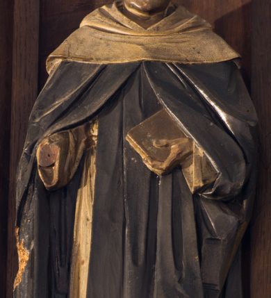 Zdjęcie nr 8: Nastawa ołtarzowa architektoniczna, jednokondygnacyjna, trójosiowa. Ołtarz kamienny, prostopadłościenny, ustawiony na dwustopniowej podstawie. Mensa kamienna, silnie wysunięta, podtrzymywana przez dwie kamienne kolumienki. Antepedium podzielone na trzy kwadratowe pola z płycinami, w środkowej wysuniętej do przodu medalion z monogramem IHS w polu. Tabernakulum w formie prostopadłościennej skrzynki, obitej fakturowaną blachą, od frontu ujęte parą kolumienek. Drzwiczki w kształcie stojącego prostokąta, dwuskrzydłowe z trybowanym przedstawieniem kielicha z unoszącą się Hostią w glorii, adorowaną przez dwa klęczące anioły. Tron do wystawiania monstrancji w formie baldachimu podtrzymywanego przez cztery kolumienki oraz z zabudowaną ścianką tylną dekorowaną rytym wzorem z czteroliści i medalionu z monogramem IHS w glorii podtrzymywanym przez parę unoszących się aniołów. Baldachim w formie dwuspadowego daszku zwieńczonego pseudowieżyczką z krzyżem; od frontu zamknięty wimpergą. Nastawa ołtarzowa ustawiona na dwustrefowym cokole z predellą dekorowaną blendami. Osie wydzielone czterema kolumnami dźwigającymi pinakle. Oś środkowa, najszersza ujęta dwiema dwustrefowymi płytkimi niszami zakończonymi trójlistnie z półpełnymi figurkami świętych: Dominika i Izydora po prawej oraz Ambrożego i Jacka po lewej; zwieńczona wimpergą, flankowaną przez dwie figurki aniołków nakryte baldachimami w formie sterczyn. W polu nisza w formie stojącego prostokąta zamkniętego łukiem trójlistnym z płaskorzeźbionym przedstawieniem Trójcy Świętej. Osie boczne z niszami w formie stojącego prostokąta zamkniętego łukiem półkolistym z figurami św. Wojciecha (po lewej) i św. Stanisława (po prawej), zamknięte dwiema wimpergami ze sterczynami oraz jednospadowym daszkiem z ażurową wieżyczką. Zwieńczenie w formie ażurowej wieżyczki z figurką św. Józefa z Dzieciątkiem, zakończonej dużą sterczyną z krzyżem dekorowaną żabkami. Struktura w kolorze naturalnego drewna, profile i ornamentyka złocone, tło pola środkowego w kolorze błękitnym, detale zielone.
