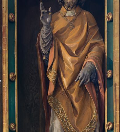 Zdjęcie nr 5: Nastawa ołtarzowa architektoniczna, jednokondygnacyjna, trójosiowa. Ołtarz kamienny, prostopadłościenny, ustawiony na dwustopniowej podstawie. Mensa kamienna, silnie wysunięta, podtrzymywana przez dwie kamienne kolumienki. Antepedium podzielone na trzy kwadratowe pola z płycinami, w środkowej wysuniętej do przodu medalion z monogramem IHS w polu. Tabernakulum w formie prostopadłościennej skrzynki, obitej fakturowaną blachą, od frontu ujęte parą kolumienek. Drzwiczki w kształcie stojącego prostokąta, dwuskrzydłowe z trybowanym przedstawieniem kielicha z unoszącą się Hostią w glorii, adorowaną przez dwa klęczące anioły. Tron do wystawiania monstrancji w formie baldachimu podtrzymywanego przez cztery kolumienki oraz z zabudowaną ścianką tylną dekorowaną rytym wzorem z czteroliści i medalionu z monogramem IHS w glorii podtrzymywanym przez parę unoszących się aniołów. Baldachim w formie dwuspadowego daszku zwieńczonego pseudowieżyczką z krzyżem; od frontu zamknięty wimpergą. Nastawa ołtarzowa ustawiona na dwustrefowym cokole z predellą dekorowaną blendami. Osie wydzielone czterema kolumnami dźwigającymi pinakle. Oś środkowa, najszersza ujęta dwiema dwustrefowymi płytkimi niszami zakończonymi trójlistnie z półpełnymi figurkami świętych: Dominika i Izydora po prawej oraz Ambrożego i Jacka po lewej; zwieńczona wimpergą, flankowaną przez dwie figurki aniołków nakryte baldachimami w formie sterczyn. W polu nisza w formie stojącego prostokąta zamkniętego łukiem trójlistnym z płaskorzeźbionym przedstawieniem Trójcy Świętej. Osie boczne z niszami w formie stojącego prostokąta zamkniętego łukiem półkolistym z figurami św. Wojciecha (po lewej) i św. Stanisława (po prawej), zamknięte dwiema wimpergami ze sterczynami oraz jednospadowym daszkiem z ażurową wieżyczką. Zwieńczenie w formie ażurowej wieżyczki z figurką św. Józefa z Dzieciątkiem, zakończonej dużą sterczyną z krzyżem dekorowaną żabkami. Struktura w kolorze naturalnego drewna, profile i ornamentyka złocone, tło pola środkowego w kolorze błękitnym, detale zielone.
