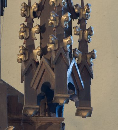 Zdjęcie nr 11: Nastawa ołtarzowa architektoniczna, jednokondygnacyjna, trójosiowa. Ołtarz kamienny, prostopadłościenny, ustawiony na dwustopniowej podstawie. Mensa kamienna, silnie wysunięta, podtrzymywana przez dwie kamienne kolumienki. Antepedium podzielone na trzy kwadratowe pola z płycinami, w środkowej wysuniętej do przodu medalion z monogramem IHS w polu. Tabernakulum w formie prostopadłościennej skrzynki, obitej fakturowaną blachą, od frontu ujęte parą kolumienek. Drzwiczki w kształcie stojącego prostokąta, dwuskrzydłowe z trybowanym przedstawieniem kielicha z unoszącą się Hostią w glorii, adorowaną przez dwa klęczące anioły. Tron do wystawiania monstrancji w formie baldachimu podtrzymywanego przez cztery kolumienki oraz z zabudowaną ścianką tylną dekorowaną rytym wzorem z czteroliści i medalionu z monogramem IHS w glorii podtrzymywanym przez parę unoszących się aniołów. Baldachim w formie dwuspadowego daszku zwieńczonego pseudowieżyczką z krzyżem; od frontu zamknięty wimpergą. Nastawa ołtarzowa ustawiona na dwustrefowym cokole z predellą dekorowaną blendami. Osie wydzielone czterema kolumnami dźwigającymi pinakle. Oś środkowa, najszersza ujęta dwiema dwustrefowymi płytkimi niszami zakończonymi trójlistnie z półpełnymi figurkami świętych: Dominika i Izydora po prawej oraz Ambrożego i Jacka po lewej; zwieńczona wimpergą, flankowaną przez dwie figurki aniołków nakryte baldachimami w formie sterczyn. W polu nisza w formie stojącego prostokąta zamkniętego łukiem trójlistnym z płaskorzeźbionym przedstawieniem Trójcy Świętej. Osie boczne z niszami w formie stojącego prostokąta zamkniętego łukiem półkolistym z figurami św. Wojciecha (po lewej) i św. Stanisława (po prawej), zamknięte dwiema wimpergami ze sterczynami oraz jednospadowym daszkiem z ażurową wieżyczką. Zwieńczenie w formie ażurowej wieżyczki z figurką św. Józefa z Dzieciątkiem, zakończonej dużą sterczyną z krzyżem dekorowaną żabkami. Struktura w kolorze naturalnego drewna, profile i ornamentyka złocone, tło pola środkowego w kolorze błękitnym, detale zielone.
